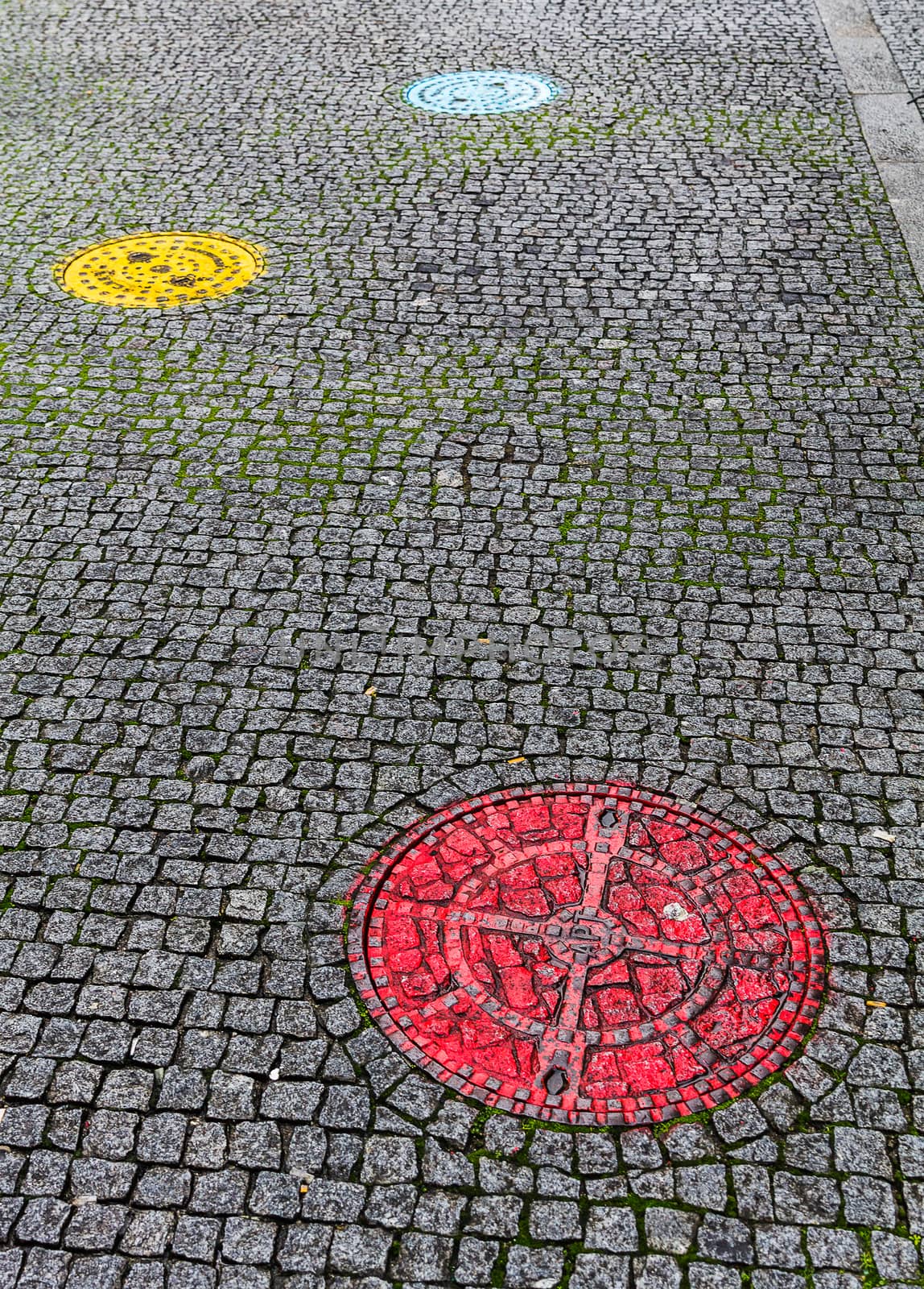 Pavement with colorful sewer covers in Porto, Portugal by JRPazos