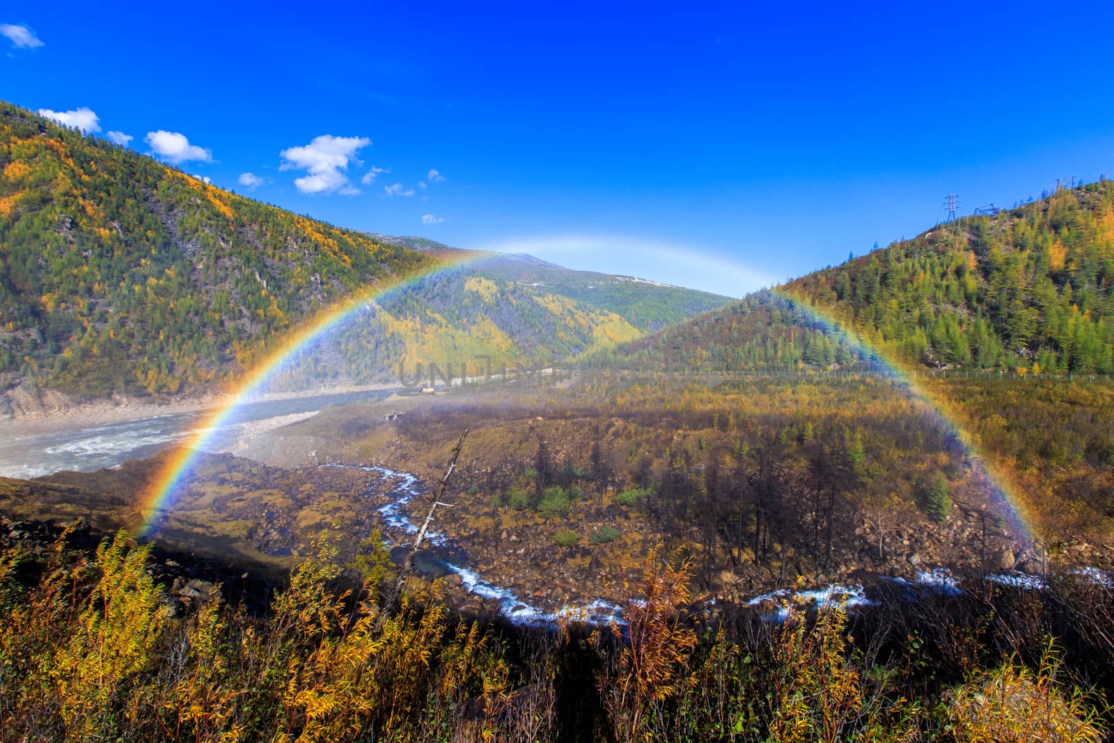 Beautiful rainbow on the background of autumn hills and the river