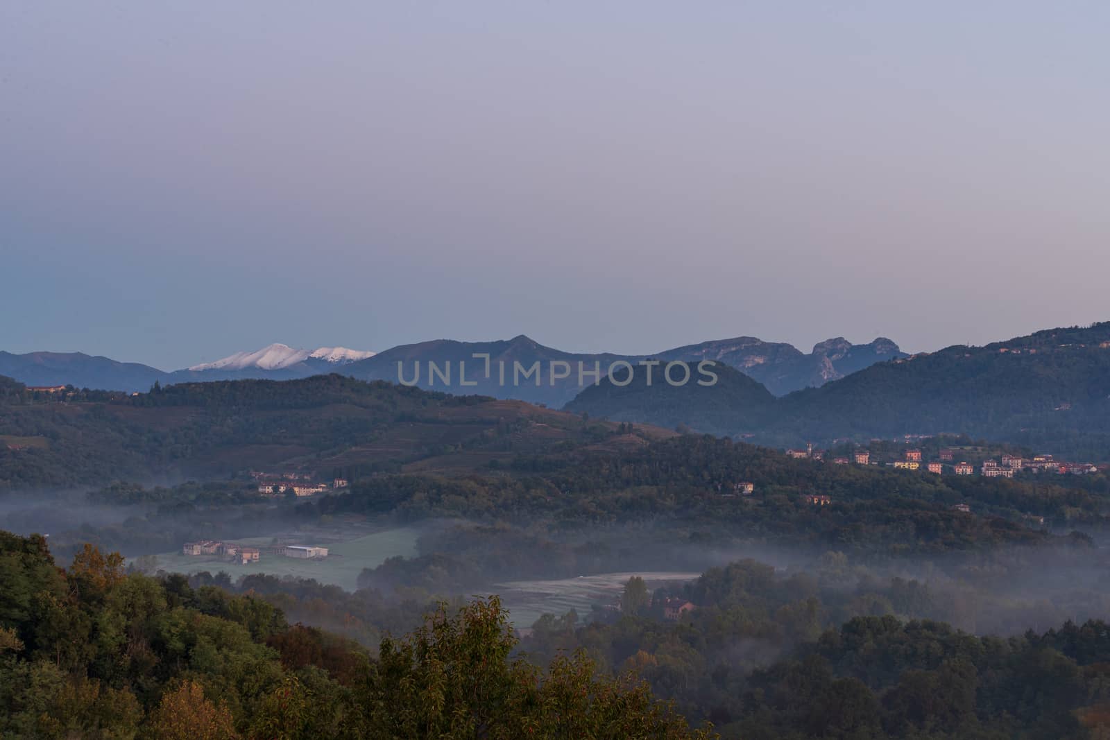 foggy landscape early in the morning, autumn panorama with snowy mountains in the background