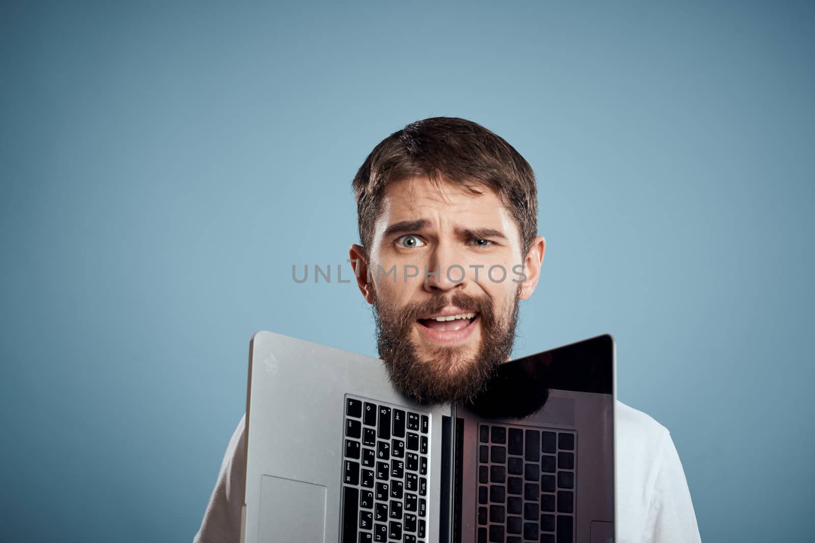 portrait of emotional man with open laptop on blue background cropped view. High quality photo