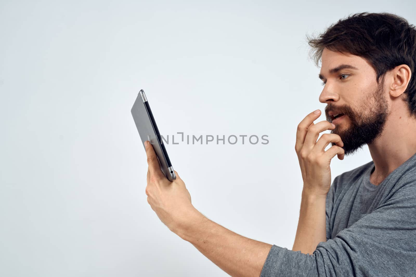 A man with a tablet in his hand internet technology communication gray jacket light background. High quality photo