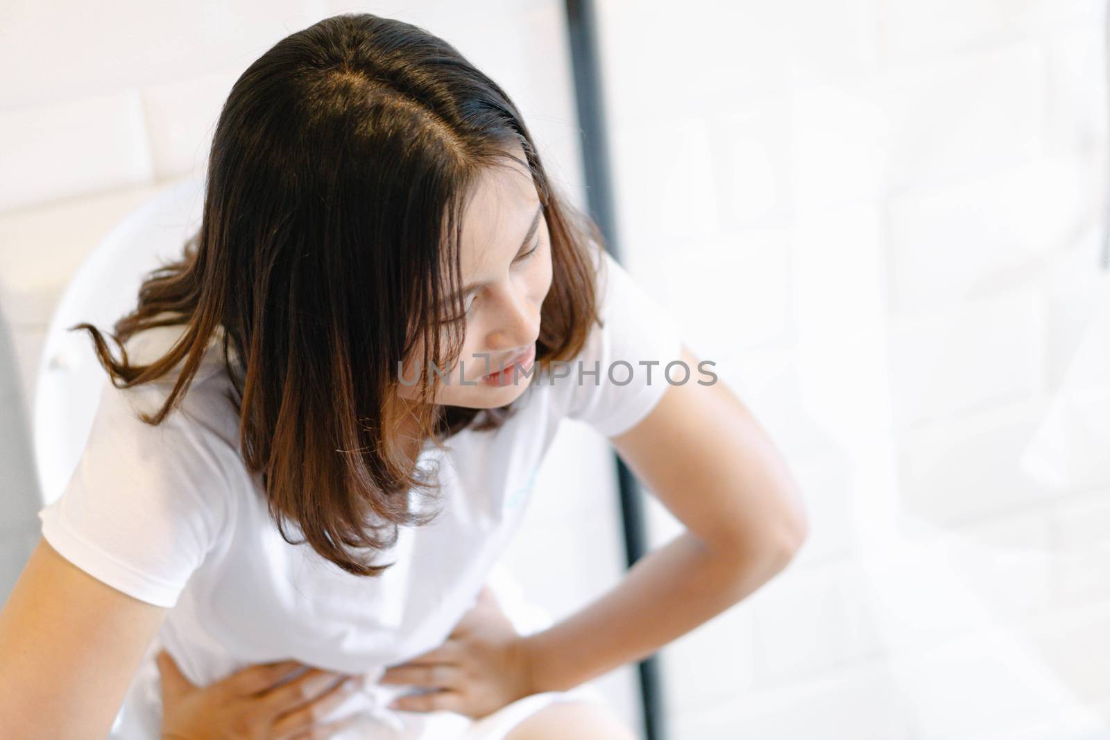 Closeup woman sitting on toilet in the morning with depressed feeling, selective focus