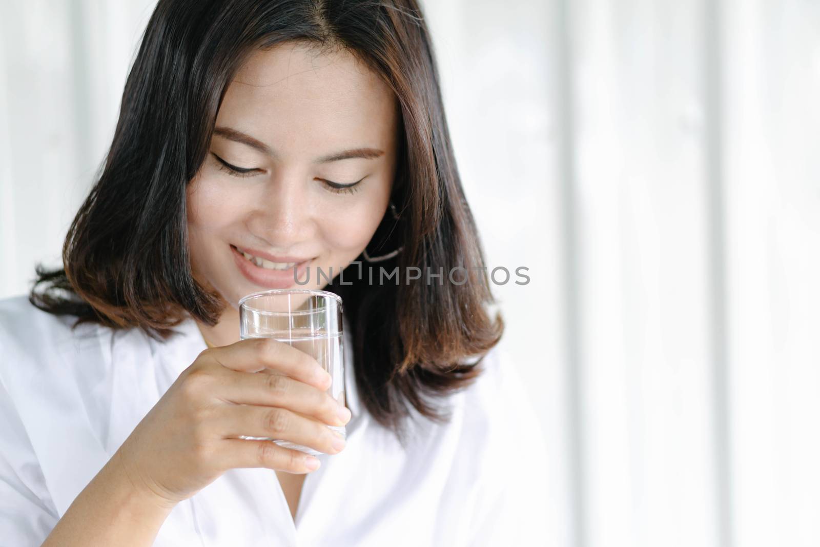 Close up woman drinking pure water from glass with light in the  by pt.pongsak@gmail.com