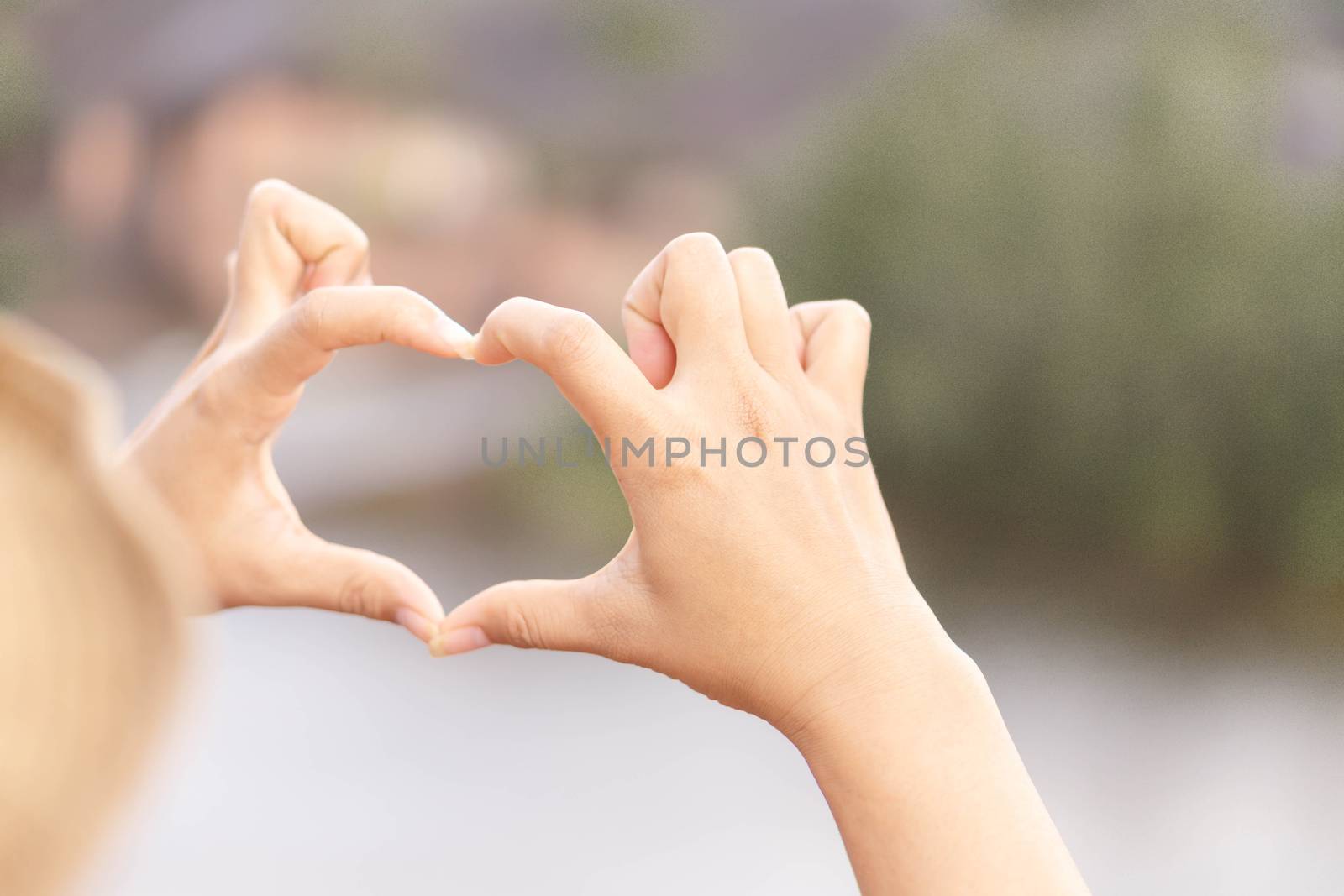 Closeup hand make heart shape with nature background, selective focus