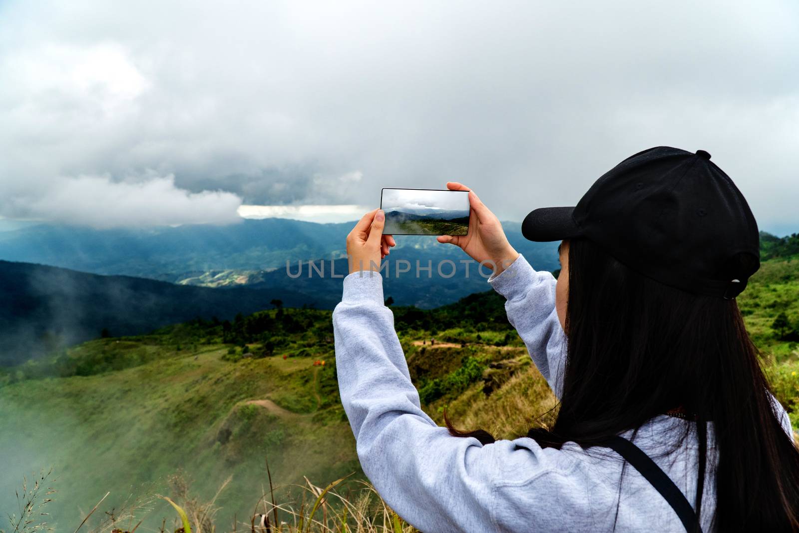 Young tourists are taking pictures of the mountain peaks and clouds