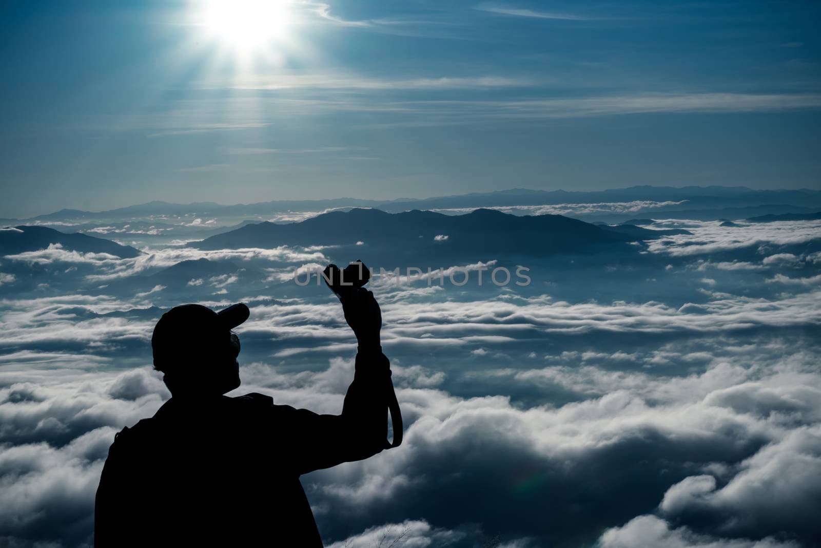 tourist man hold camara with sunrise and sea of fog view on phu chi fa mountain area and national forest park in chiang rai, Thailand.