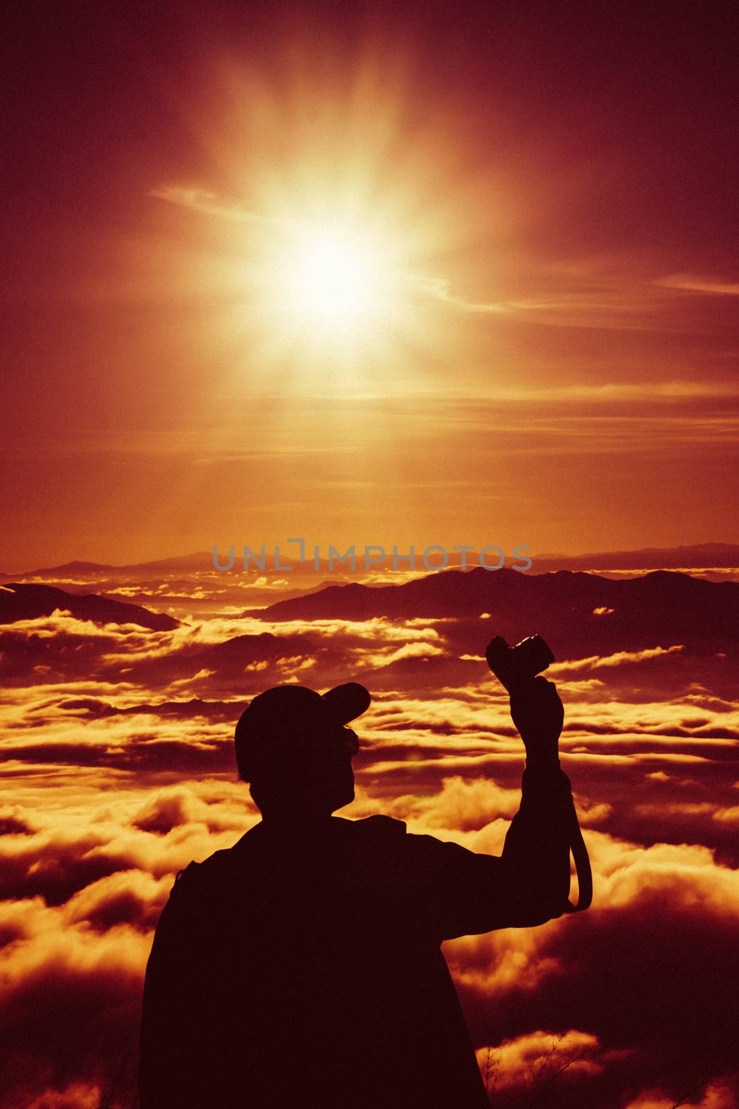 tourist man hold camara with sunrise and sea of fog view on phu chi fa mountain area and national forest park in chiang rai, Thailand.