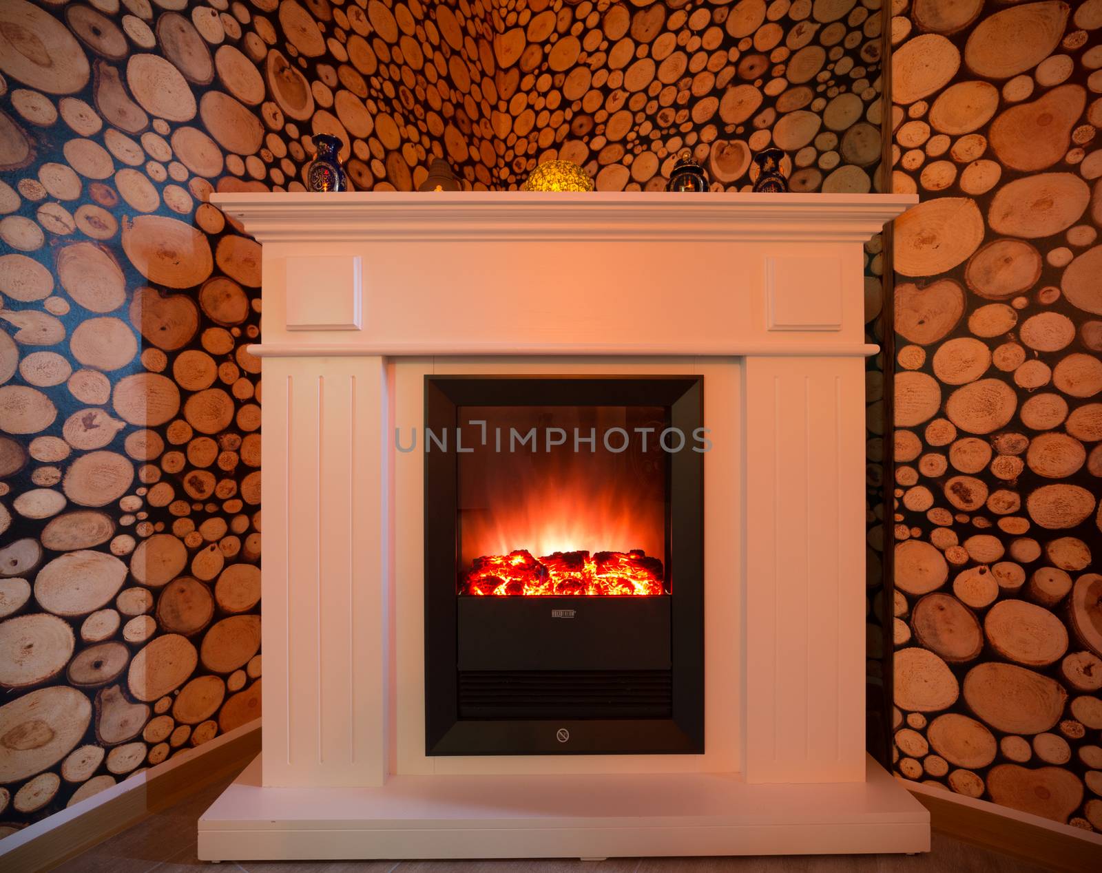 A burning fireplace in the room. White beautiful fireplace.