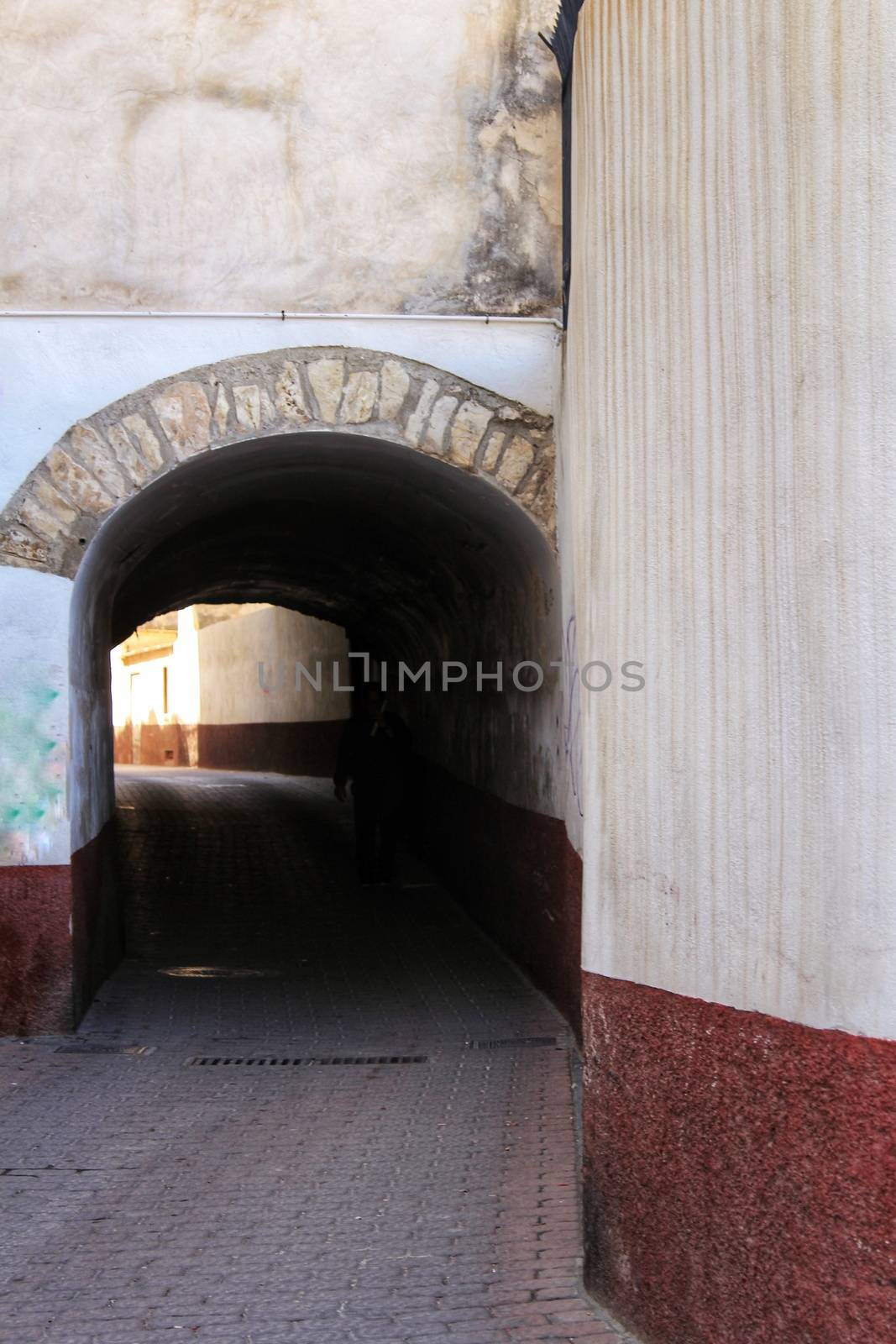 Narrow street with dark tunnel in Caravaca de la Cruz, Murcia, Spain