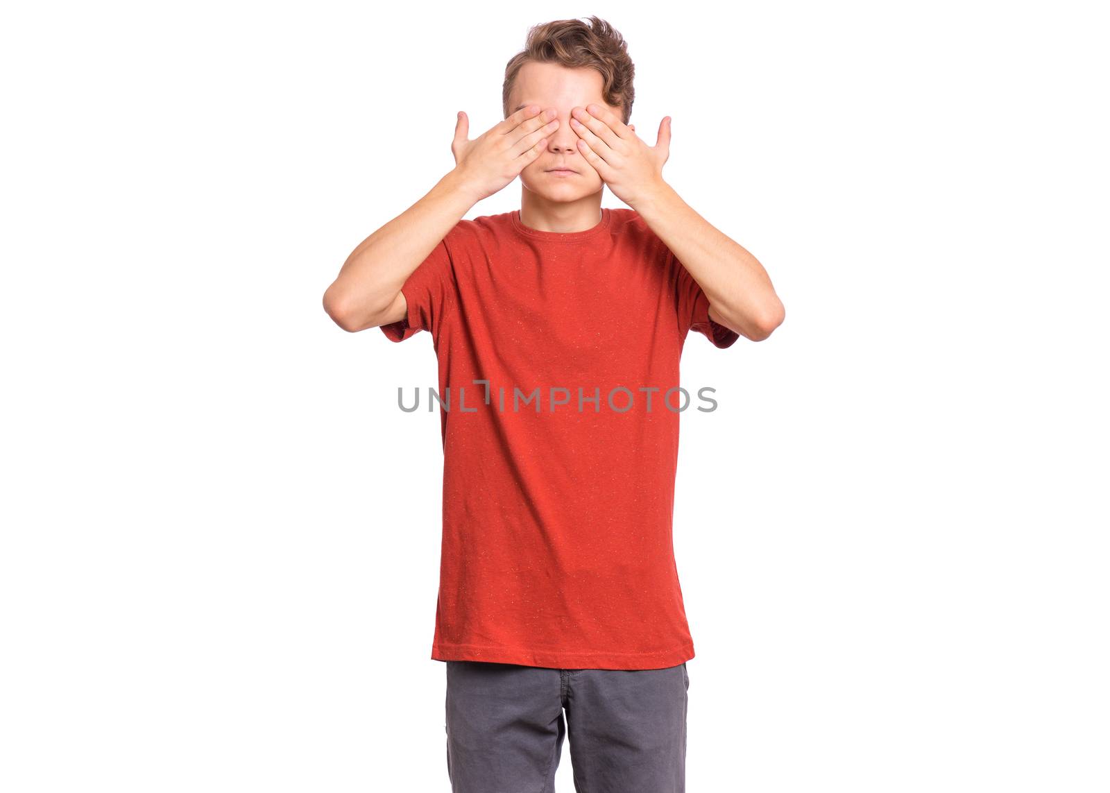 Handsome teen boy with sad expression covering face with hands while crying, isolated on white background