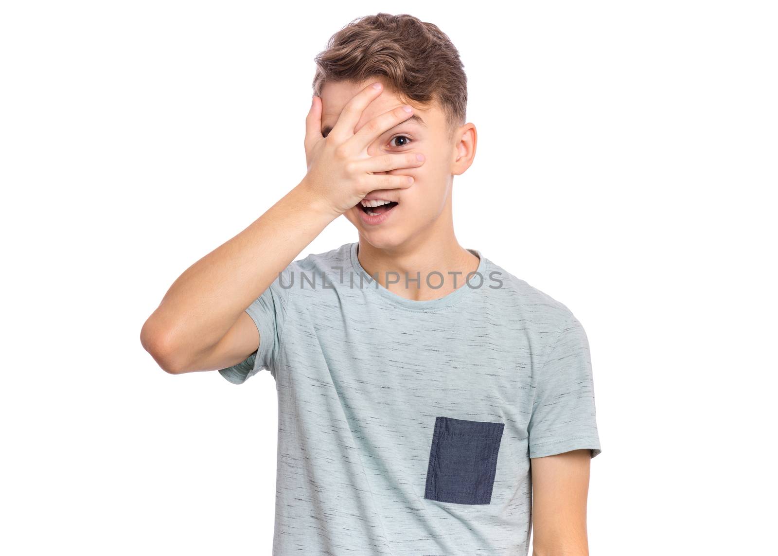 Surprised handsome teen boy covering his eyes with hand, isolated on white background