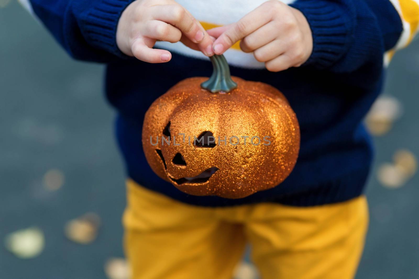 Kid's hands holding a toy pumpkin lantern for the holiday halloween by galinasharapova