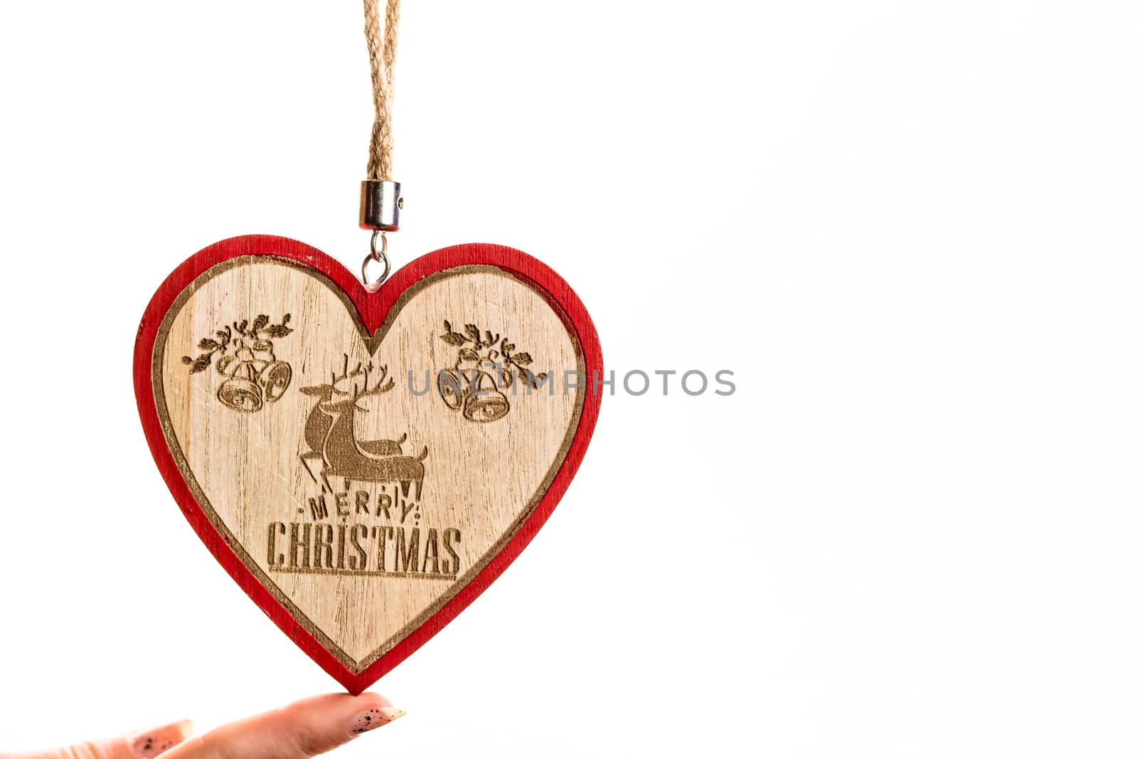 Hand holding heart shaped Christmas decoration isolated on white.