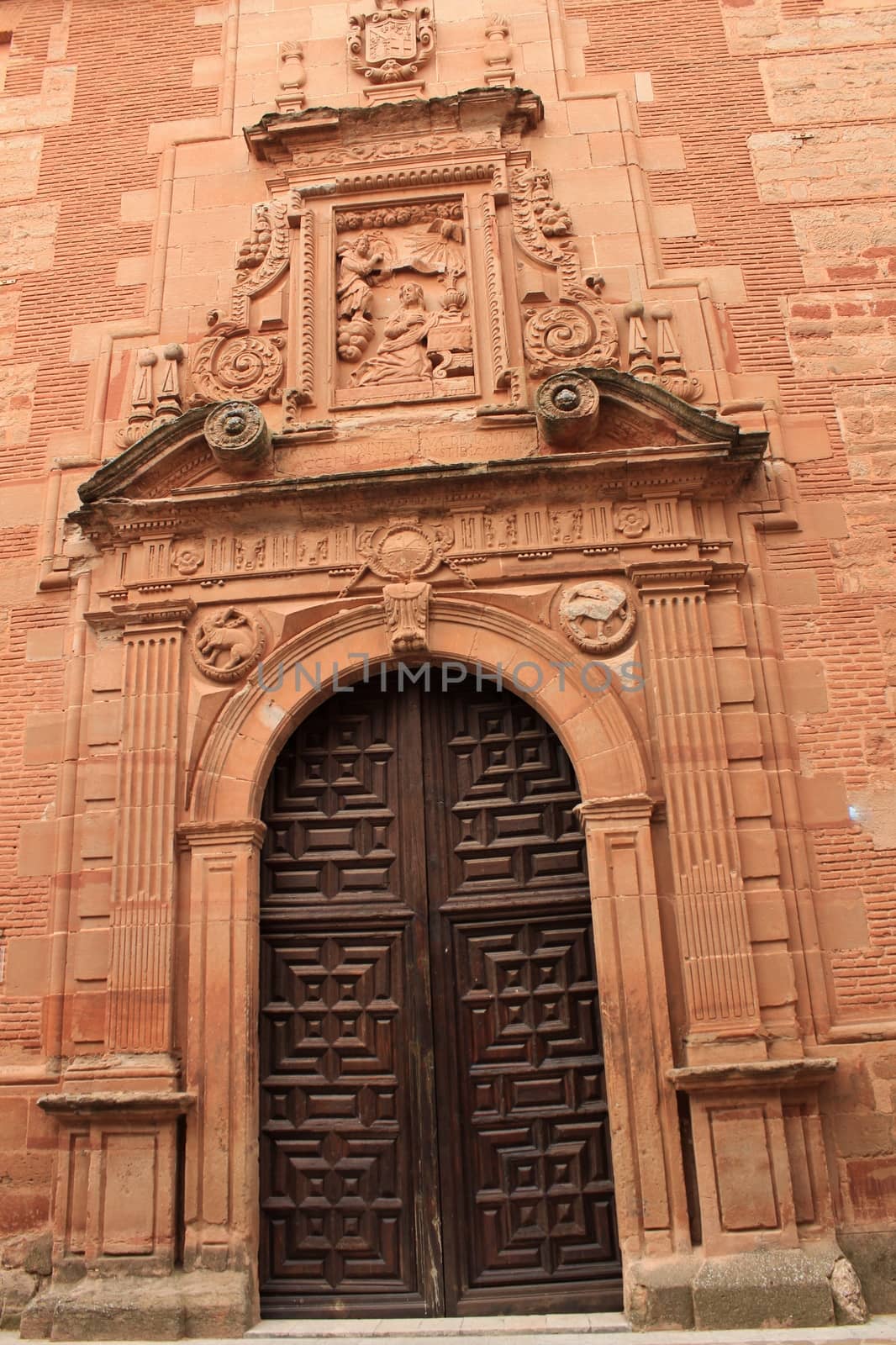 Old stone facade made of carved stone and vintage wooden door in a majestic house in Villanueva de los Infantes, Ciudad Real community, Spain. Encarnacion convent facade.