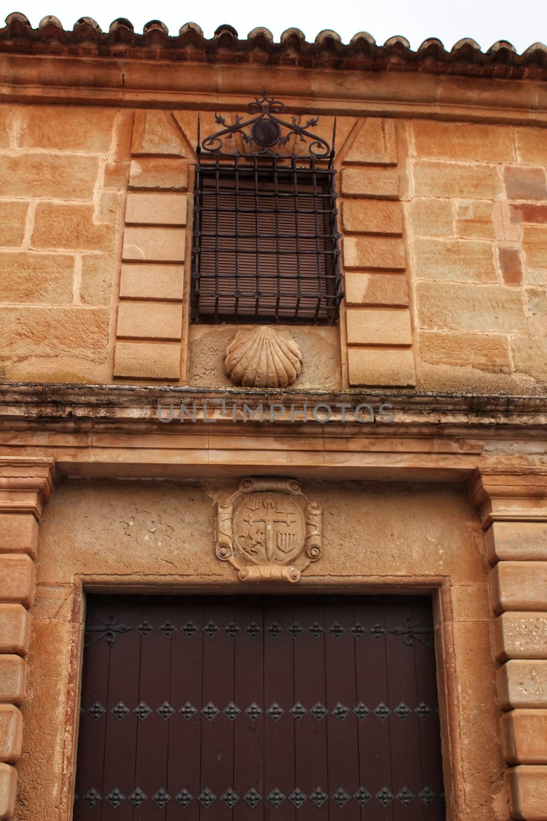 Old stone facade made of carved stone and vintage wooden door in a majestic house in Villanueva de los Infantes, Ciudad Real community, Spain