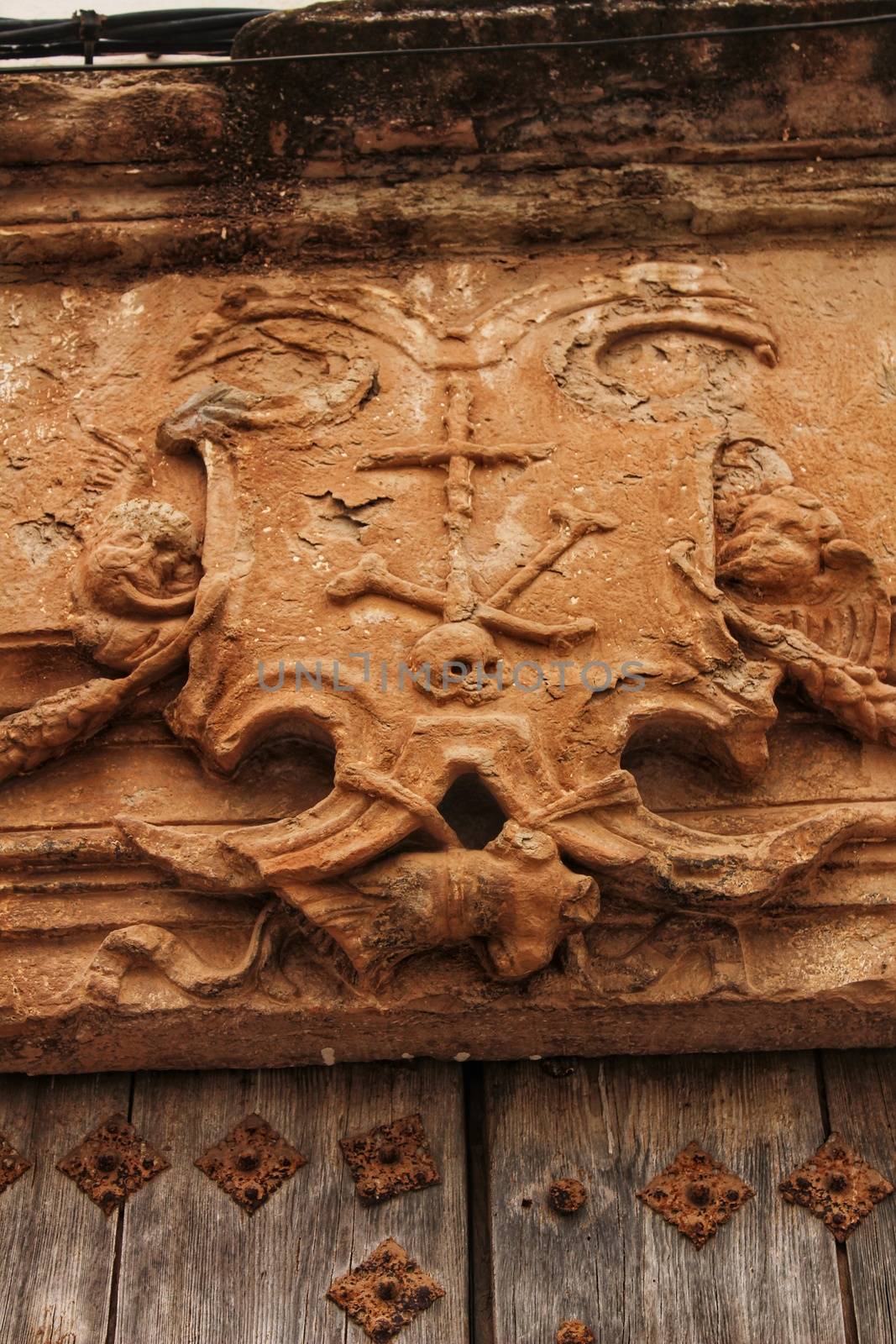 Old wooden door and coat of arms of the Holy Inquisition in a house in Villanueva de los Infantes, Castile-la Mancha, Spain