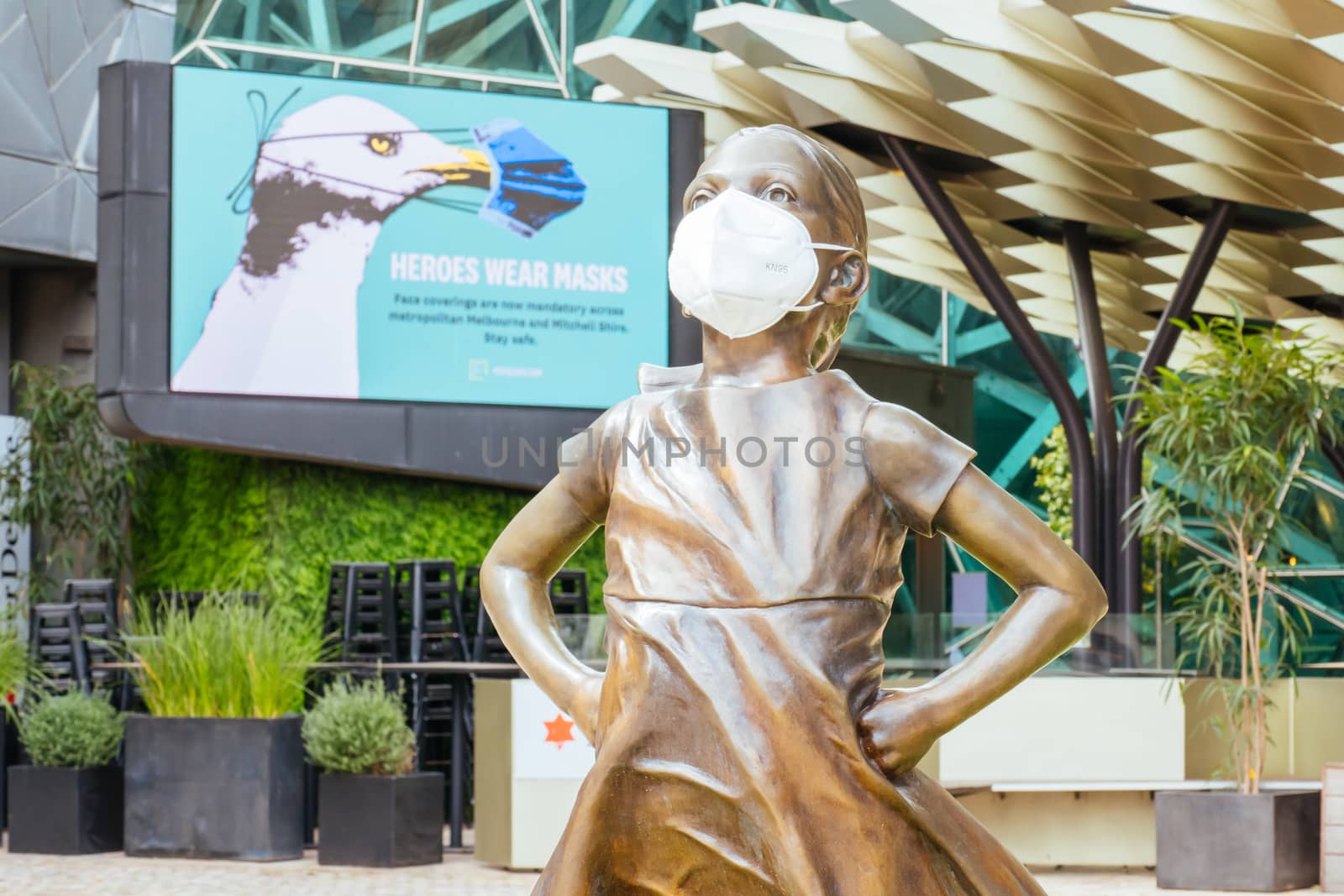Melbourne, Australia - October 10th 2020: Federation Square and a masked statue of Fearless Girl in Melbourne is quiet and empty during the Coronavirus pandemic and associated lockdown.