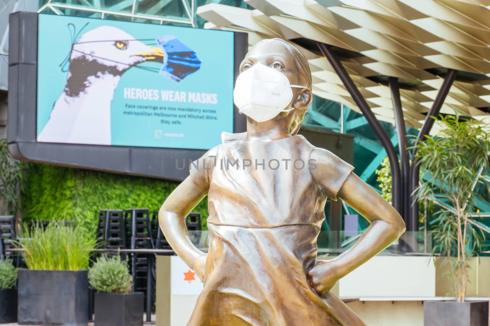 Melbourne, Australia - October 10th 2020: Federation Square and a masked statue of Fearless Girl in Melbourne is quiet and empty during the Coronavirus pandemic and associated lockdown.