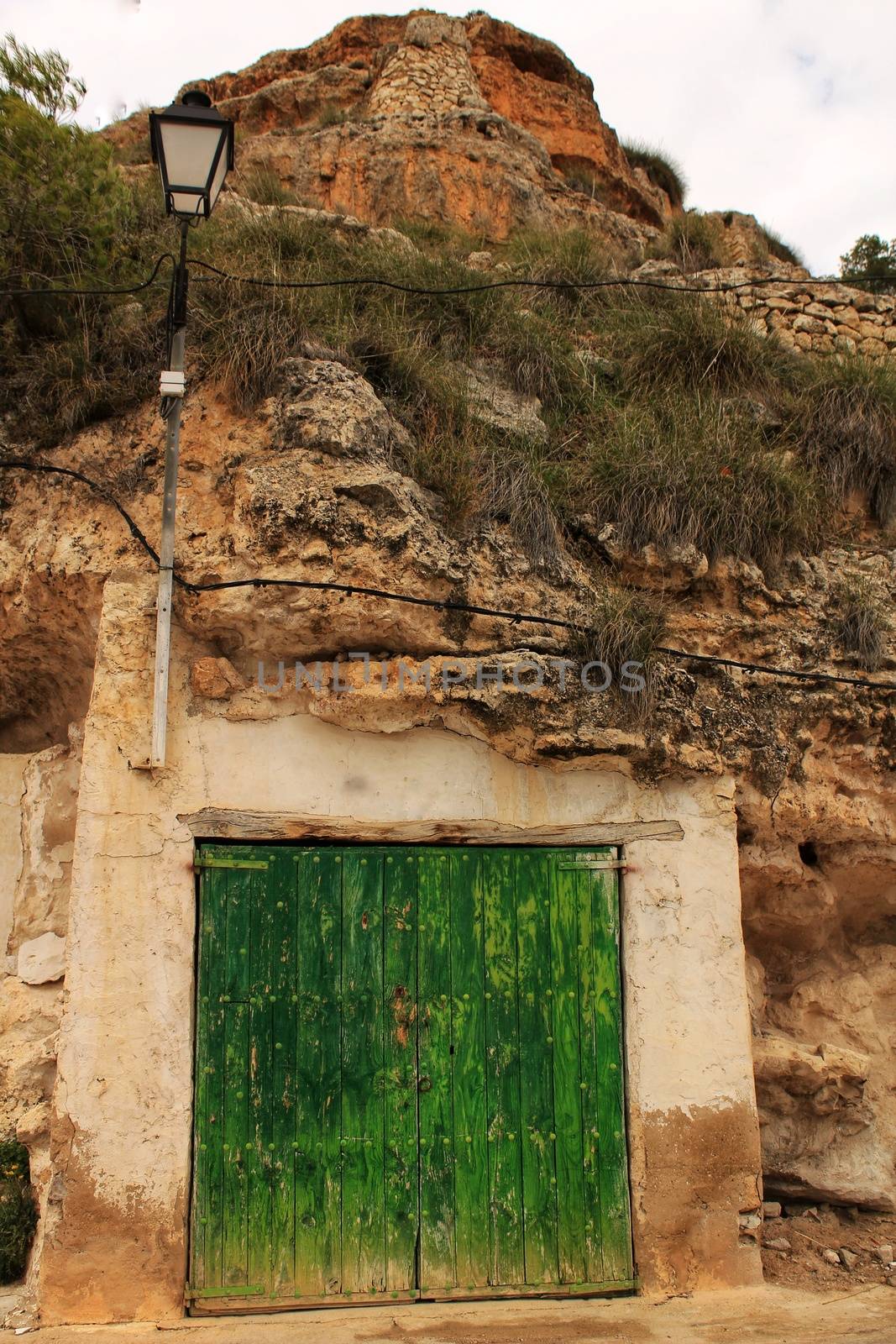 Old garage with green wooden door excavated in the mountain by soniabonet