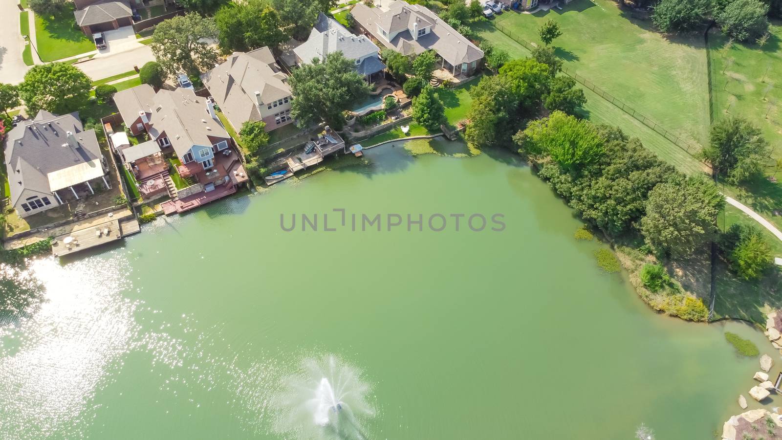 Flyover waterfront and park side houses with lake fountain in sunny day near Dallas, Texas, USA by trongnguyen
