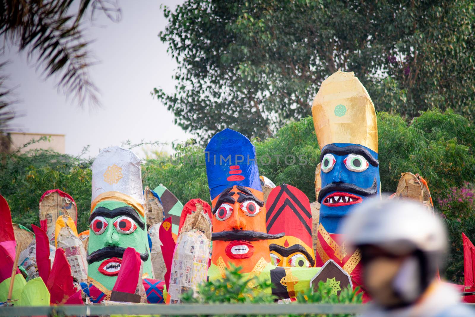 colorful ravana effigies placed on a busy street with traffic passing by to be purchased and filled with fireworks for the hindu festival of dussehra or vijay dashmi celebrating the victory of good over evil as given in the indian epic of ramayana