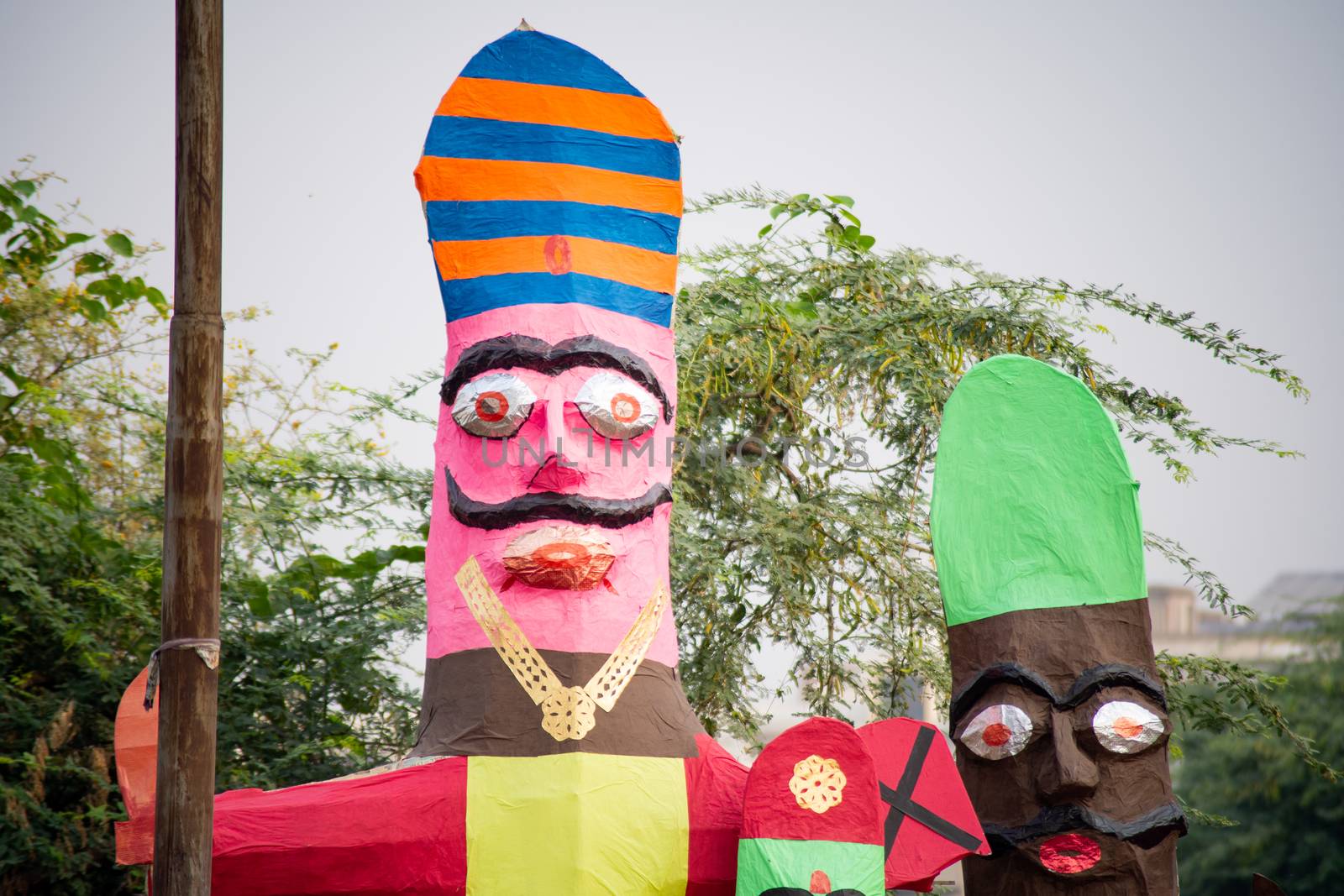 colorful ravana effigies placed on a busy street with traffic passing by to be purchased and filled with fireworks for the hindu festival of dussehra by Shalinimathur