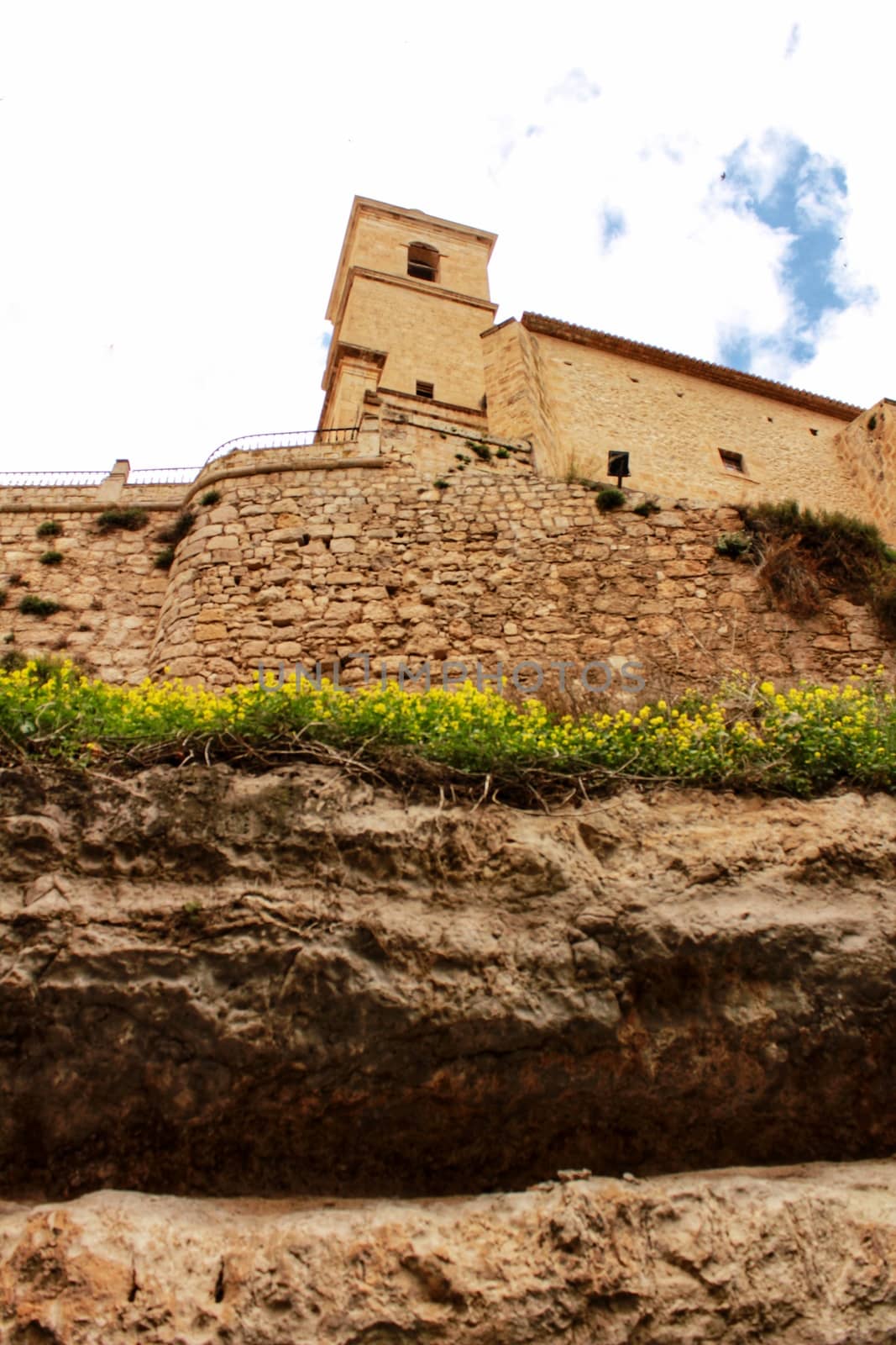 Beautiful overview of the town of Alcala de Jucar with the fortress castle and the church in spring under gray sky