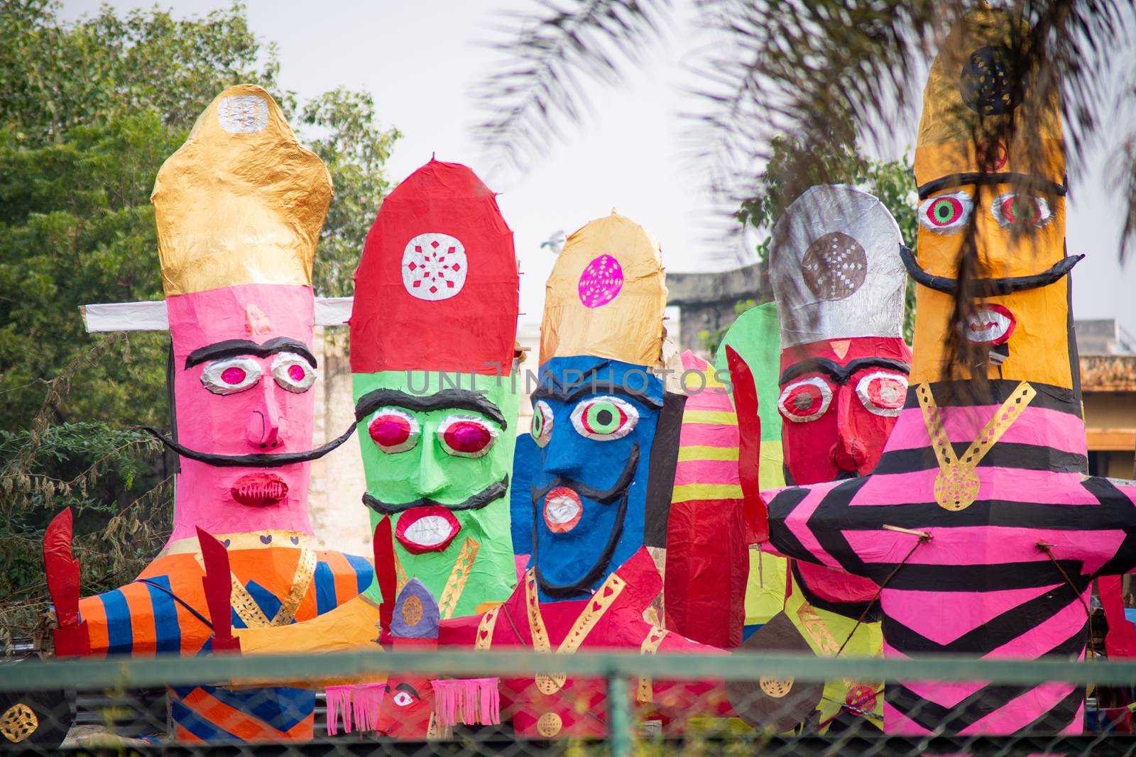 colorful ravana effigies placed on a busy street with traffic passing by to be purchased and filled with fireworks for the hindu festival of dussehra by Shalinimathur