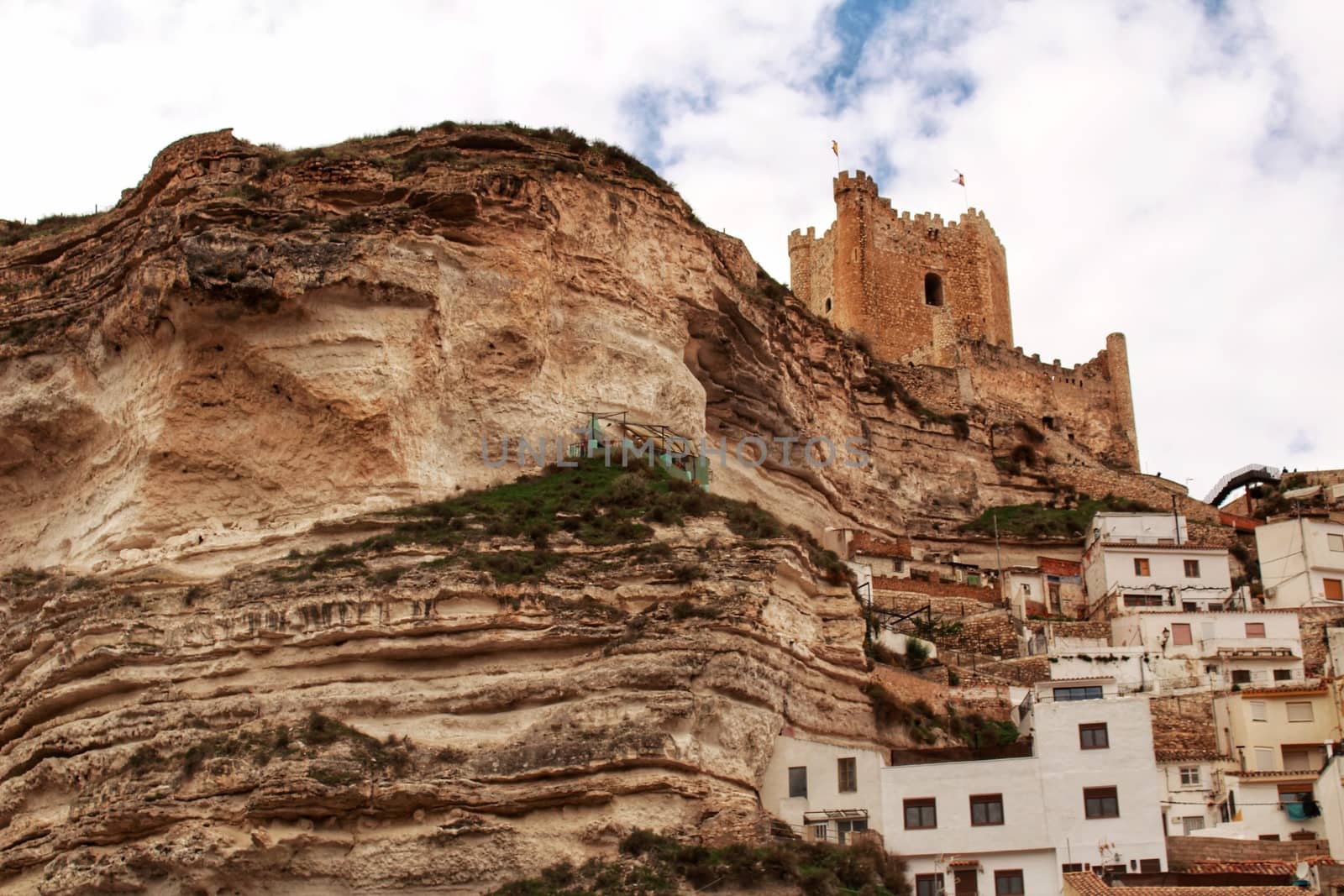 Beautiful overview of the town of Alcala de Jucar with the fortress castle and the church in spring under gray sky