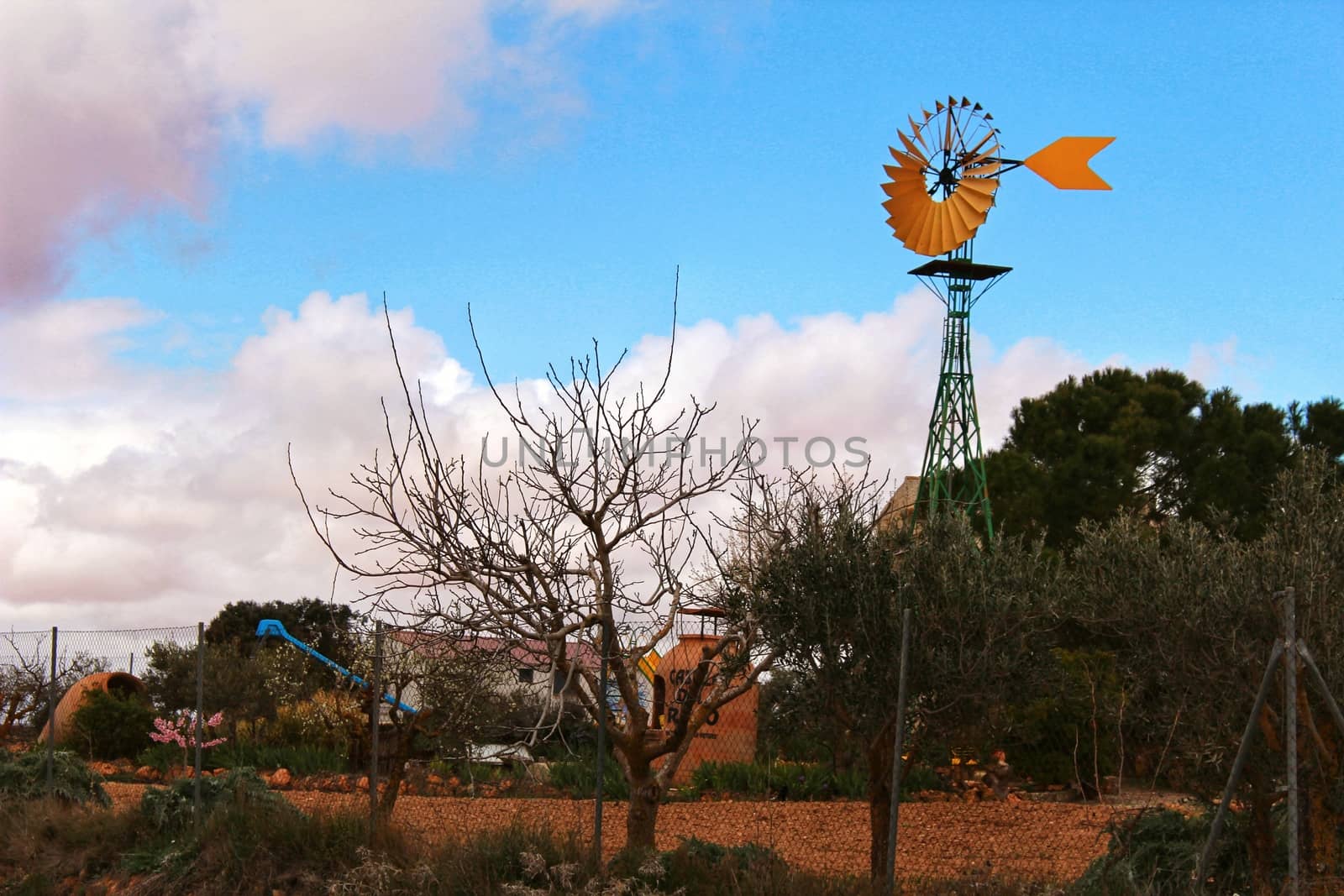 Yellow windmill with tale vane under cloudy and windy weather by soniabonet