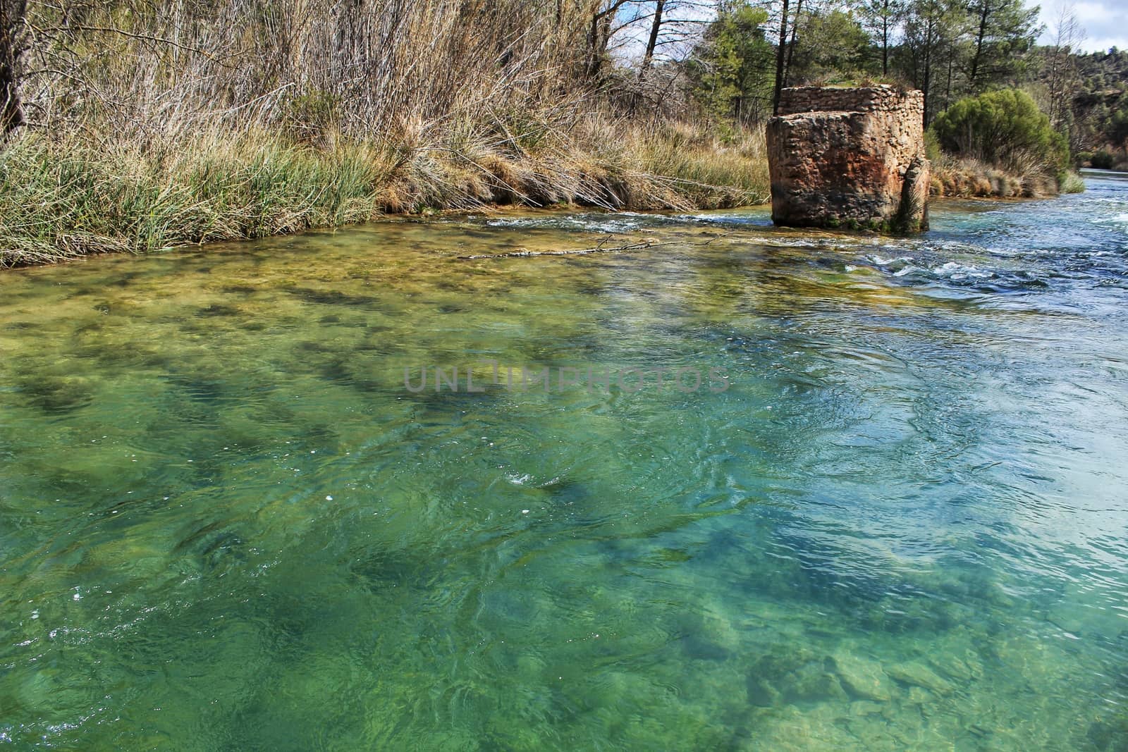 Cabriel River with crystal clear waters and surrounded by green vegetation in the mountains of Albacete, Spain