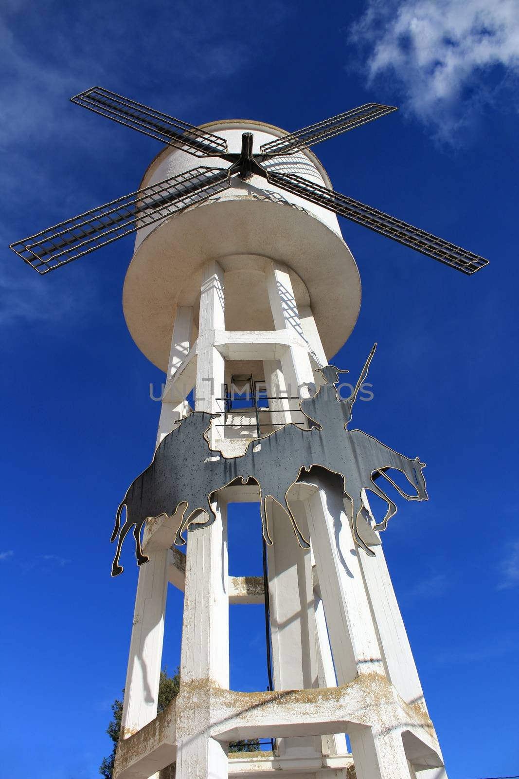Water tank shaped like a windmill under blue sky by soniabonet