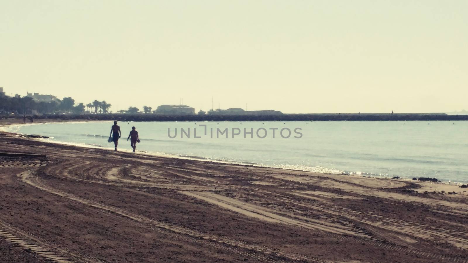 Couple walking by the seashore in a sunny in Santa Pola by soniabonet
