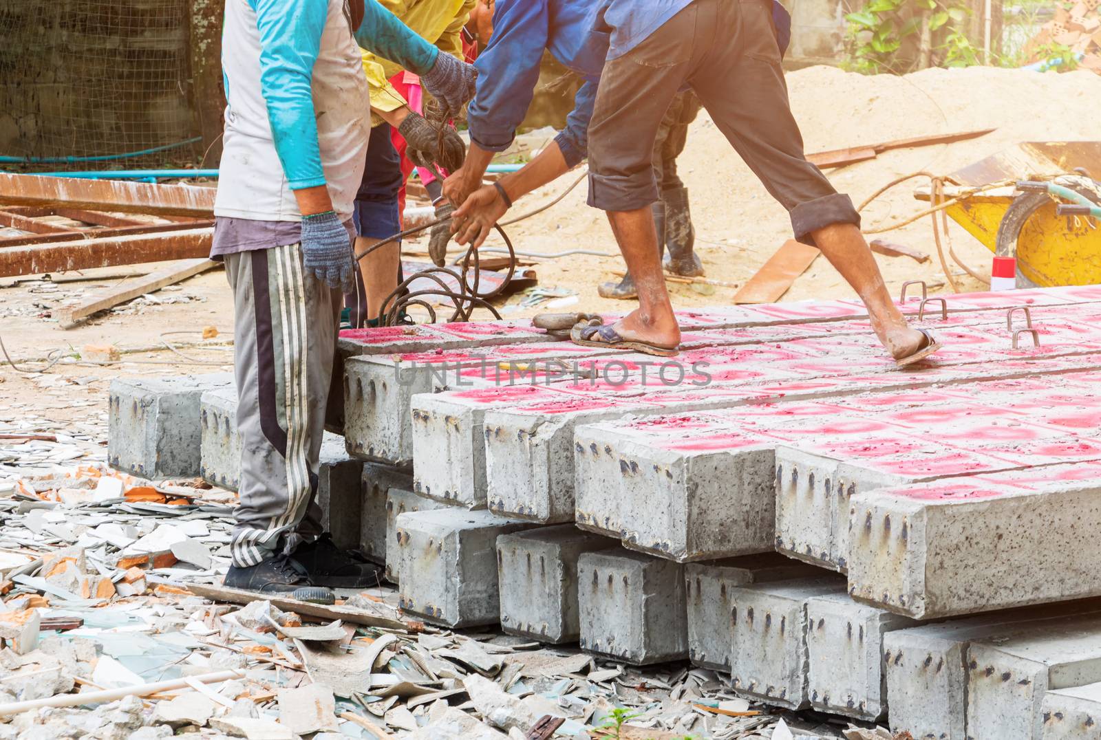 worker move pile concrete pillars on ground by pramot