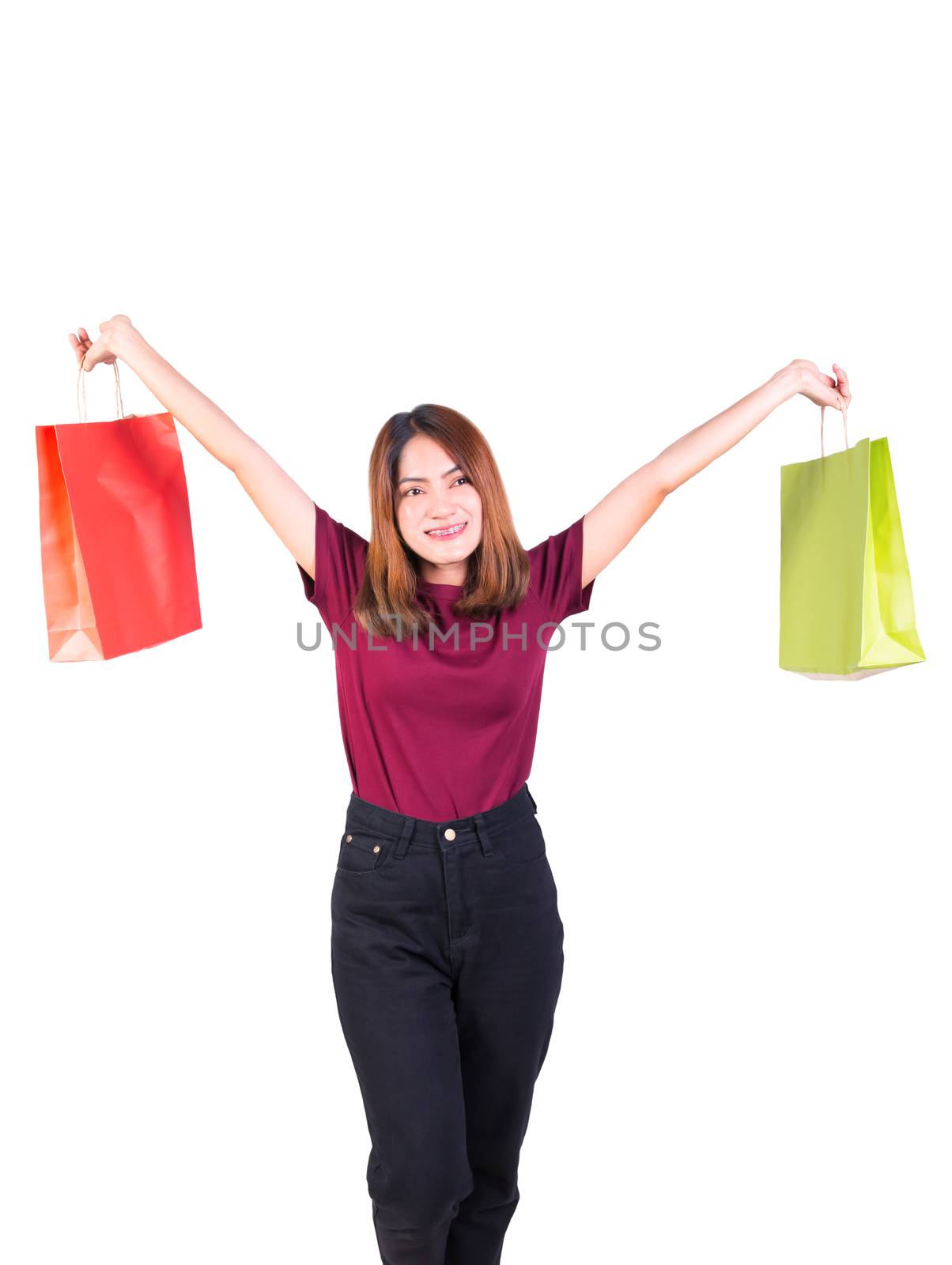 young woman pretty smiling holding paper bags green and orange shopping. on white background and looking at camera