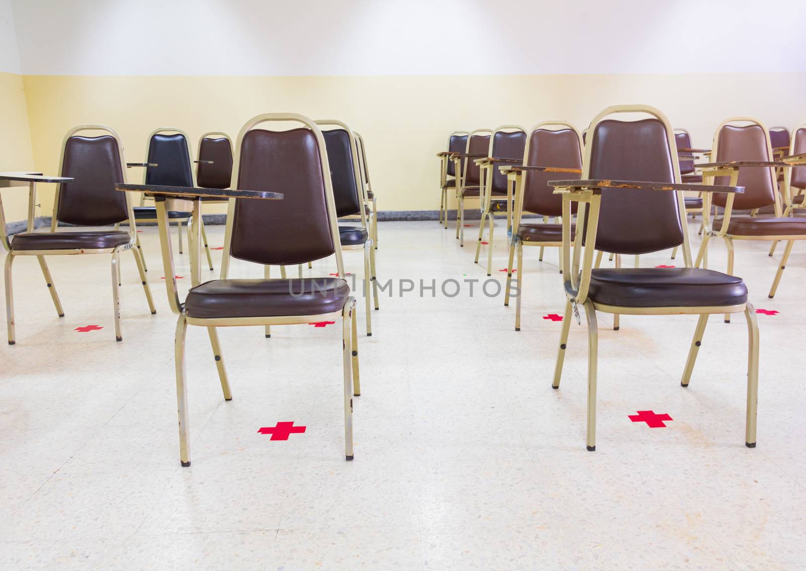 old lecture chairs empty in classroom with social distancing by pramot