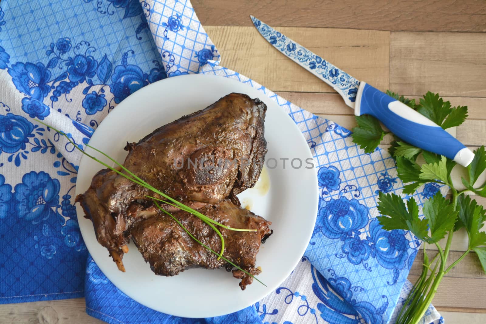 Roasted hare legs on rustic wooden surface with blue and white decoration