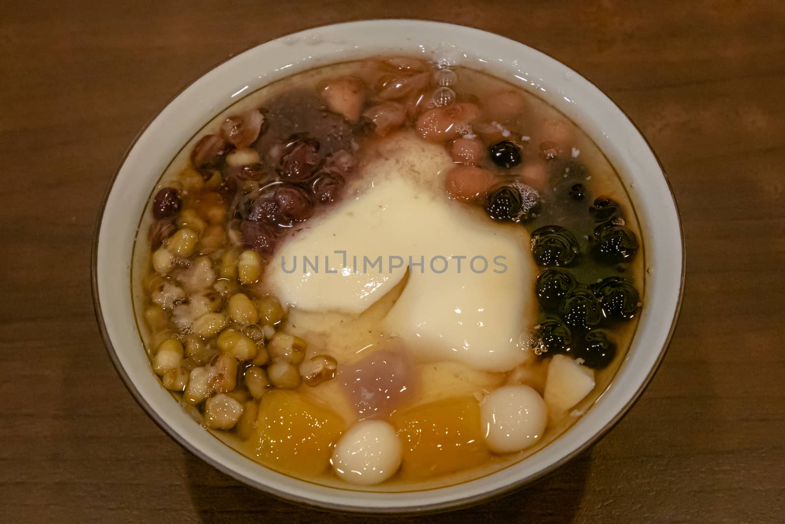 Taiwanese tofu pudding dessert (Dou Hua) on brown table at street food market in Taiwan. by phasuthorn