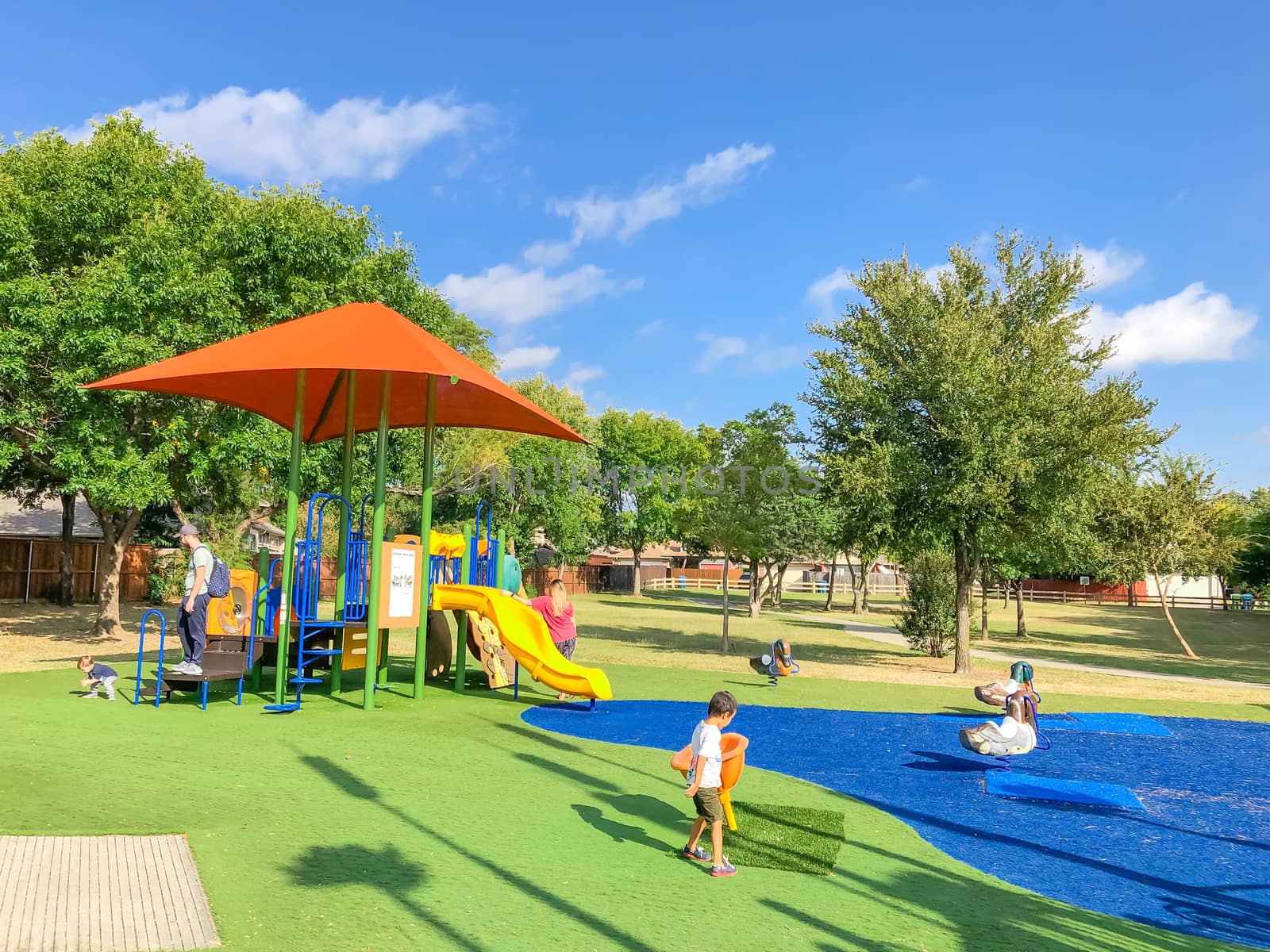 Modern playground with sun shade sails, artificial grass and kids playing in Flower Mound, Texas, USA by trongnguyen