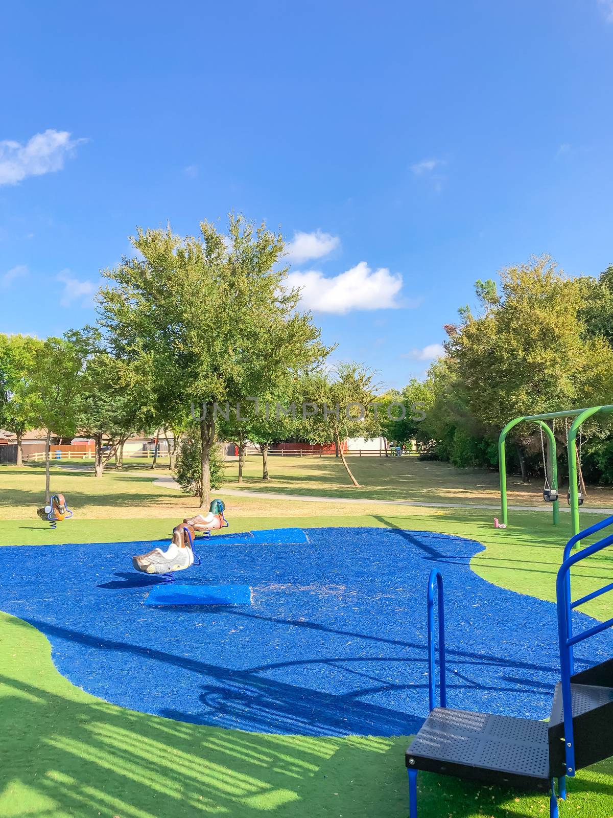 Neighborhood playground with artificial grass in Flower Mound, Texas, America. Suburban recreational facility surrounded by wooden fence