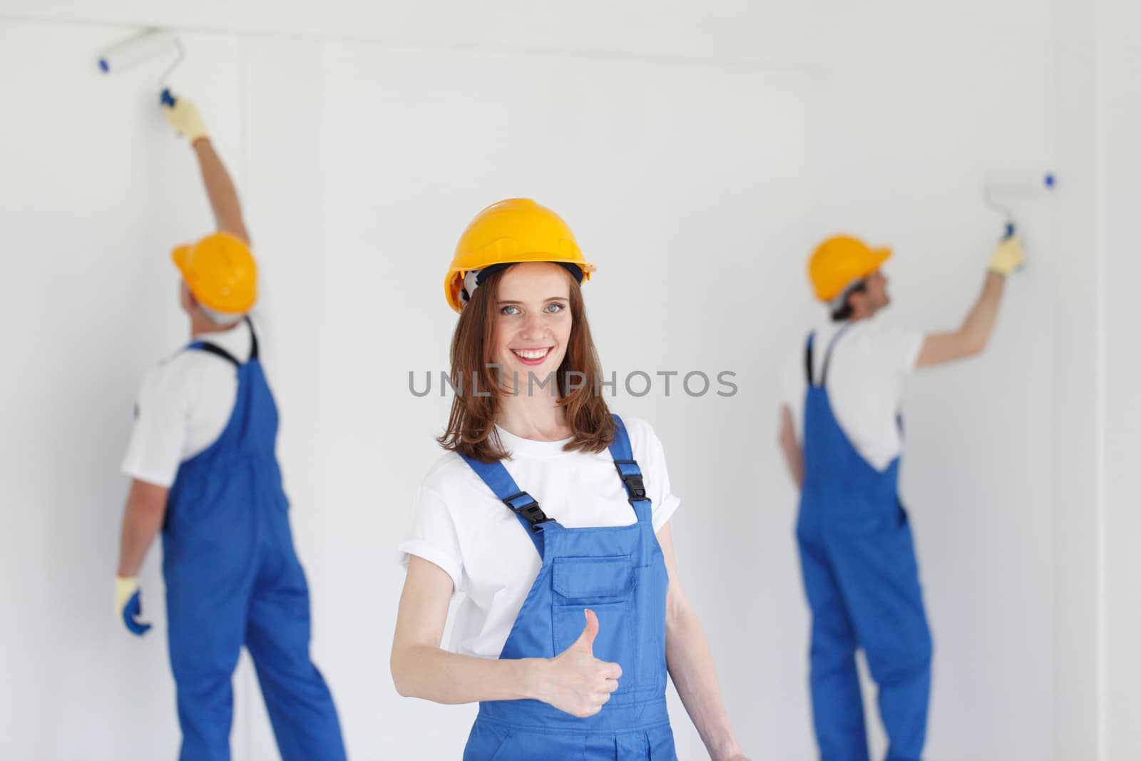 Female worker gives thumbs up in front of two painters