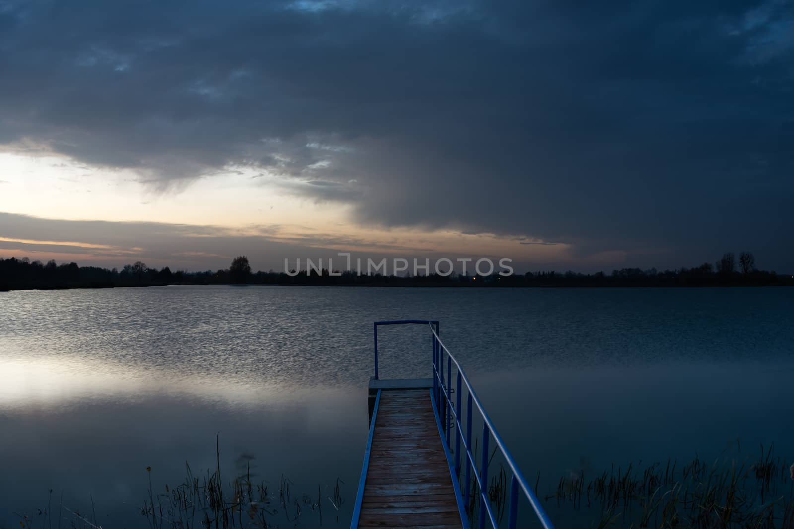 Bridge towards the lake and dark evening clouds, october view