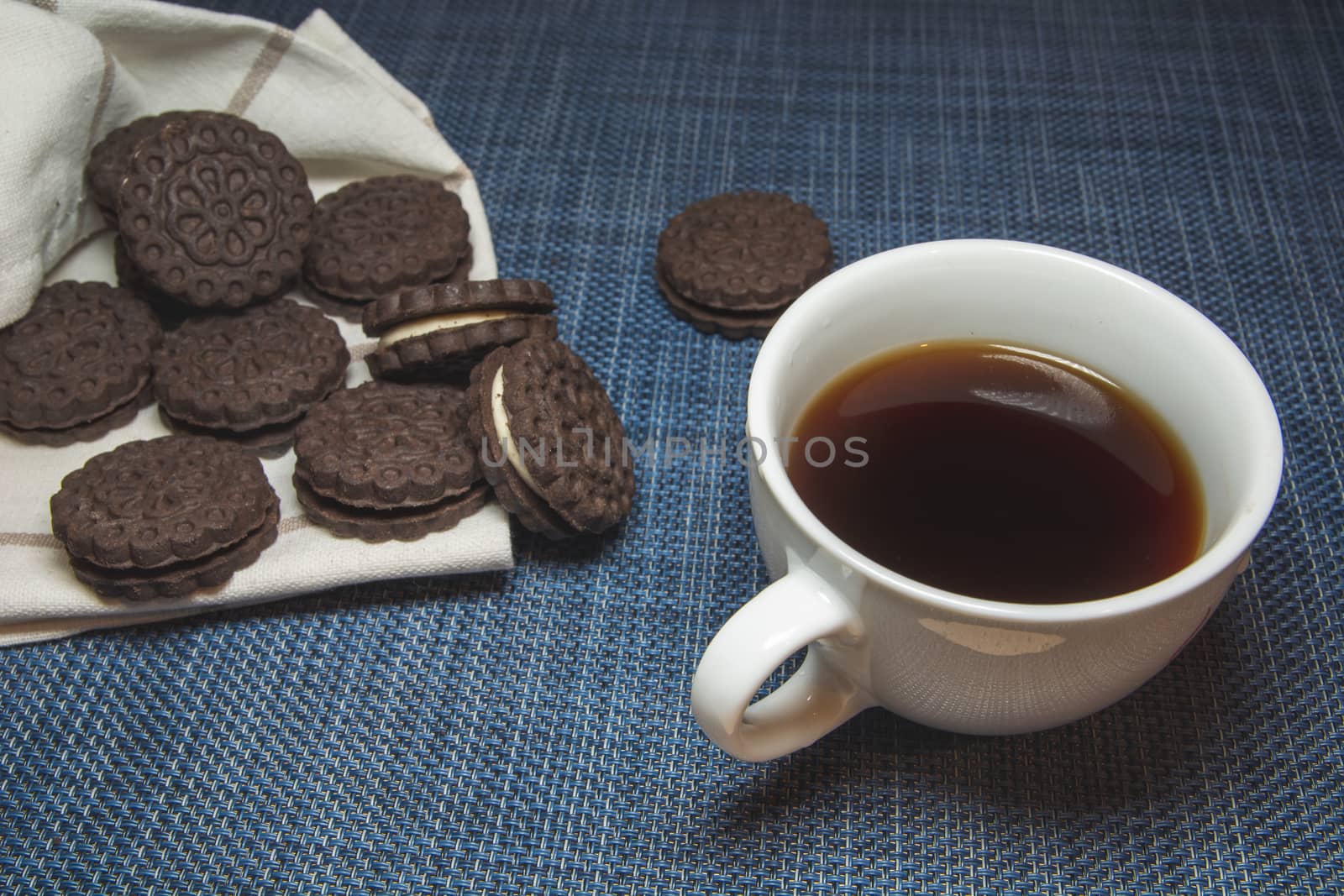 Coffee in a cup and brown cookies on a blue background