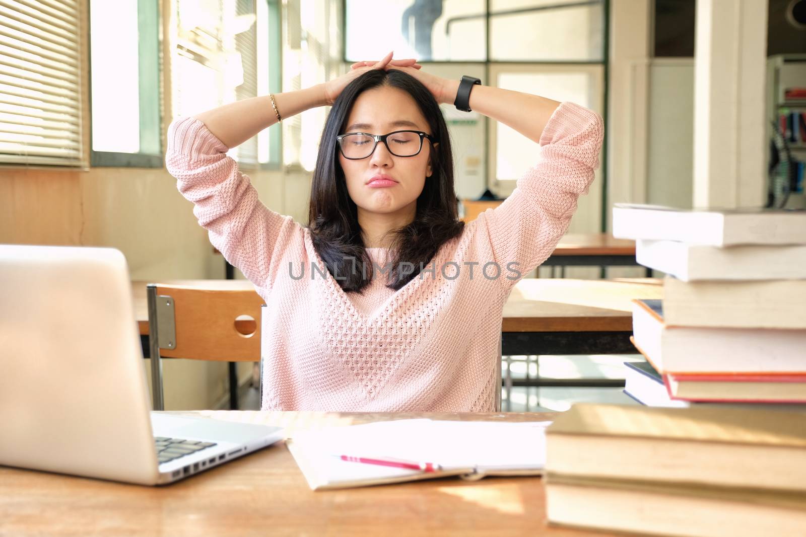 Young woman studying in a library and thinking of something by Surasak