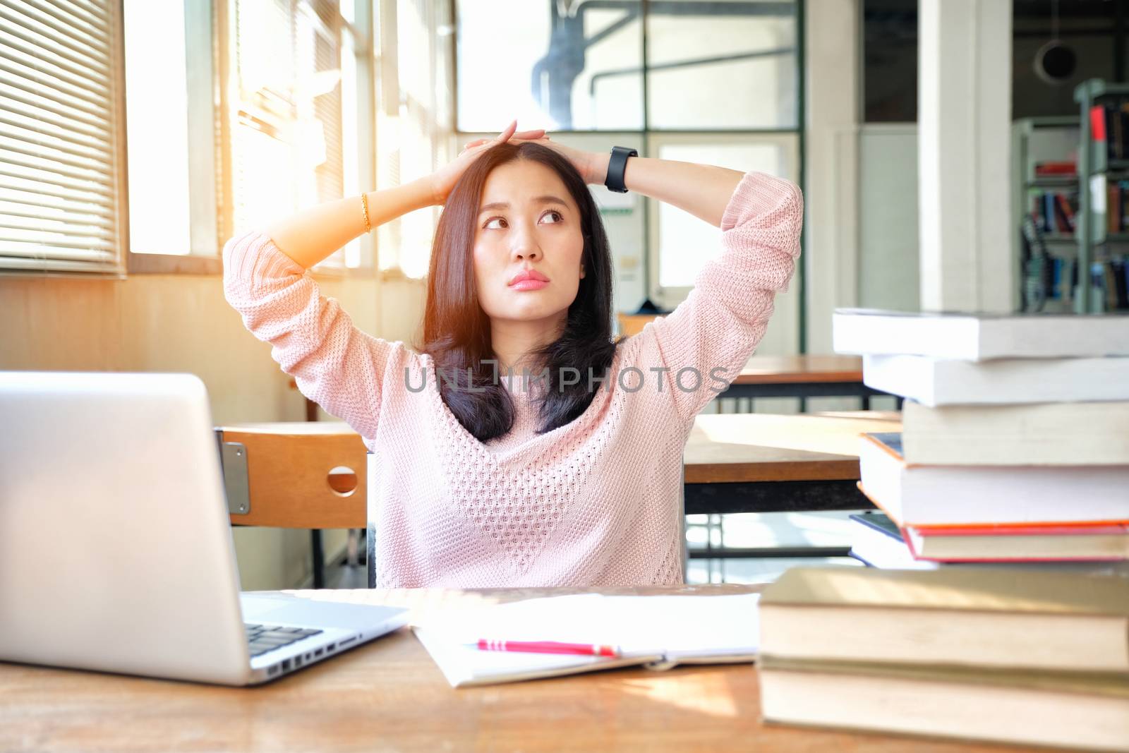 Young woman studying in a library and thinking of something