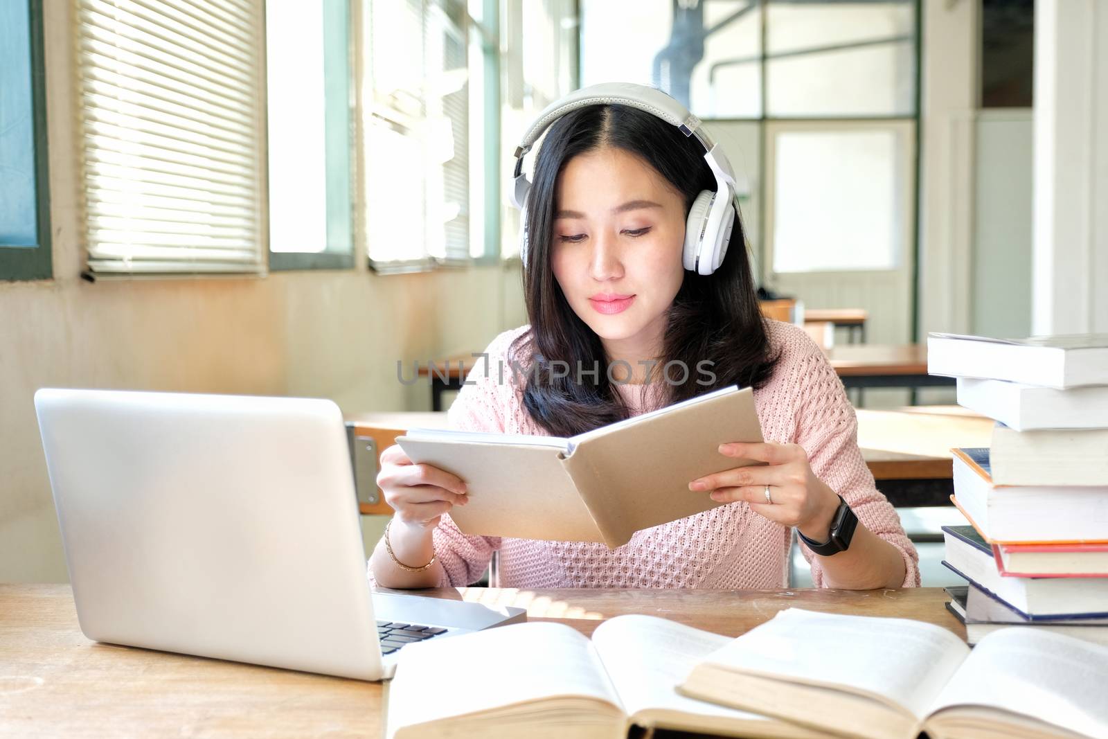 Young woman in a good mood listening to music  while studying in by Surasak