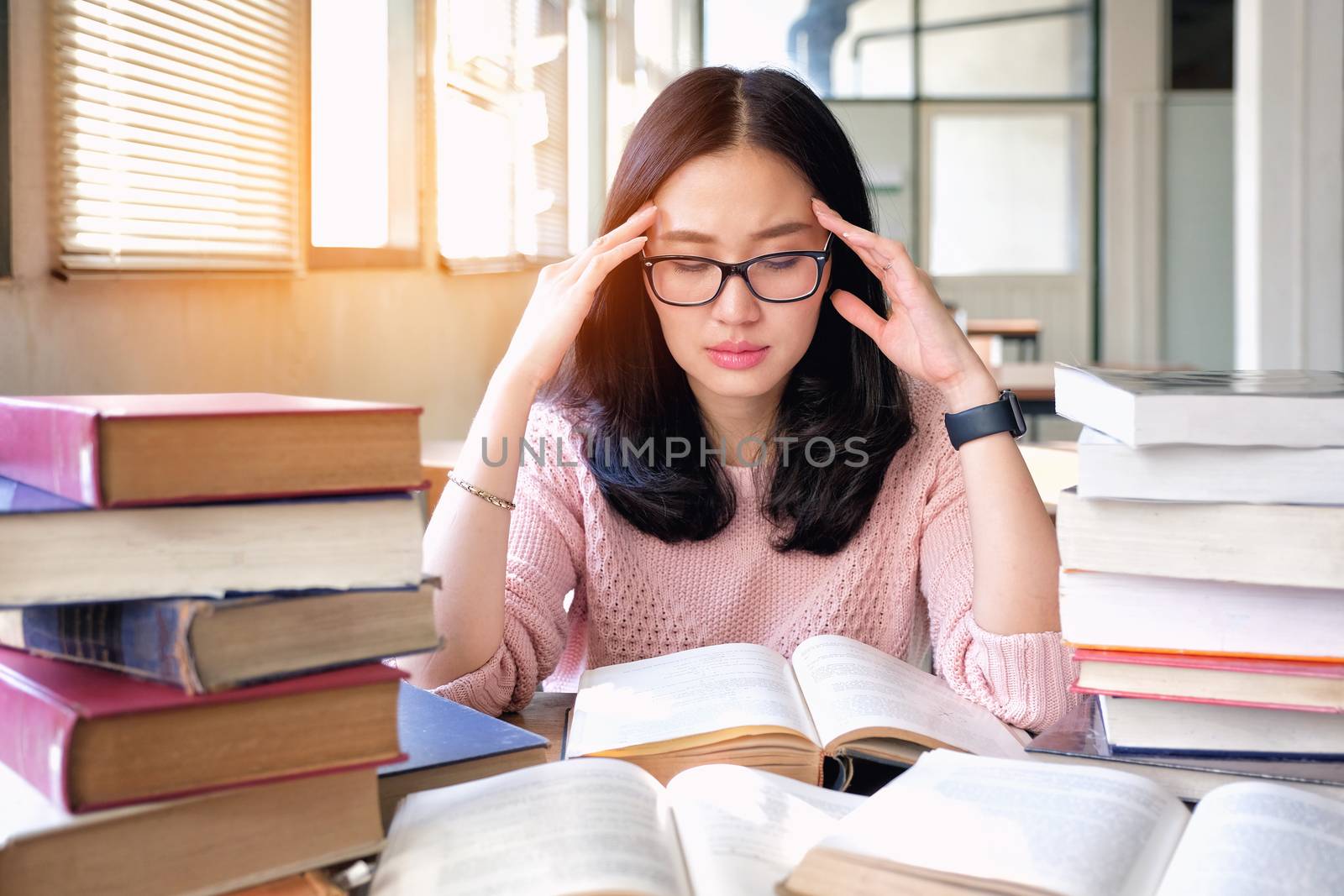 Young woman thinking while studying in library by Surasak