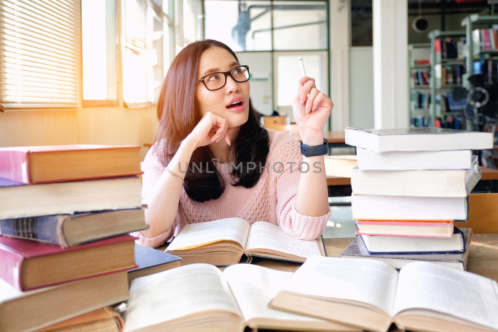 Young woman thinking while studying in library