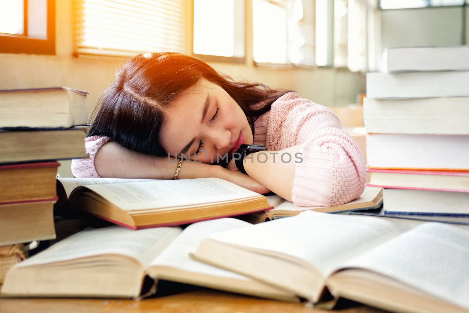 Young woman sleeping in library by Surasak