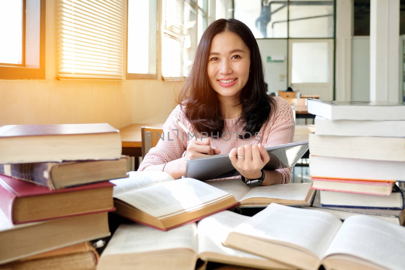 Young woman using tablet in a library by Surasak